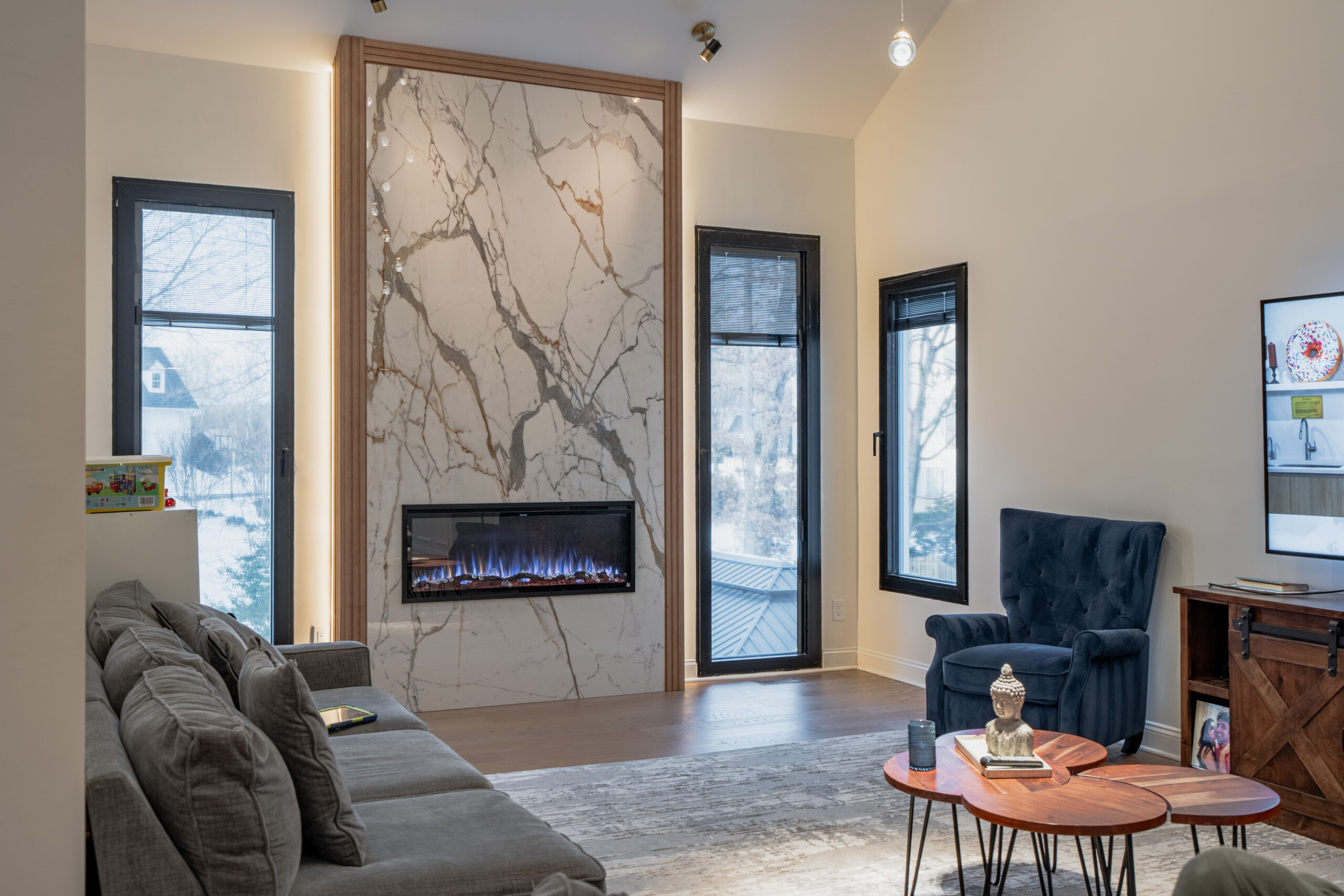 living room with tall marble fireplace wall, modern seating, and large windows