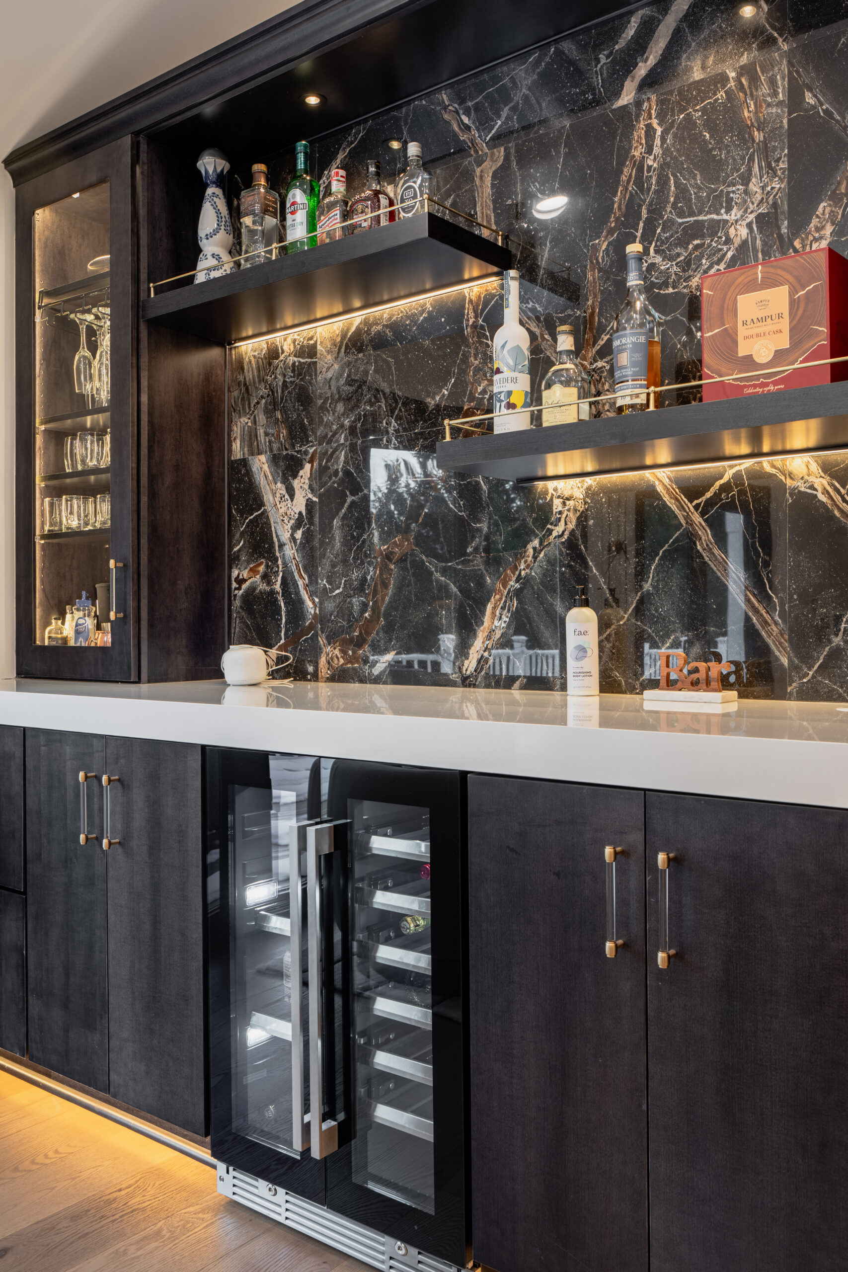 custom home bar with dark cabinets, marble backsplash wall, open shelves, and built-in wine cooler