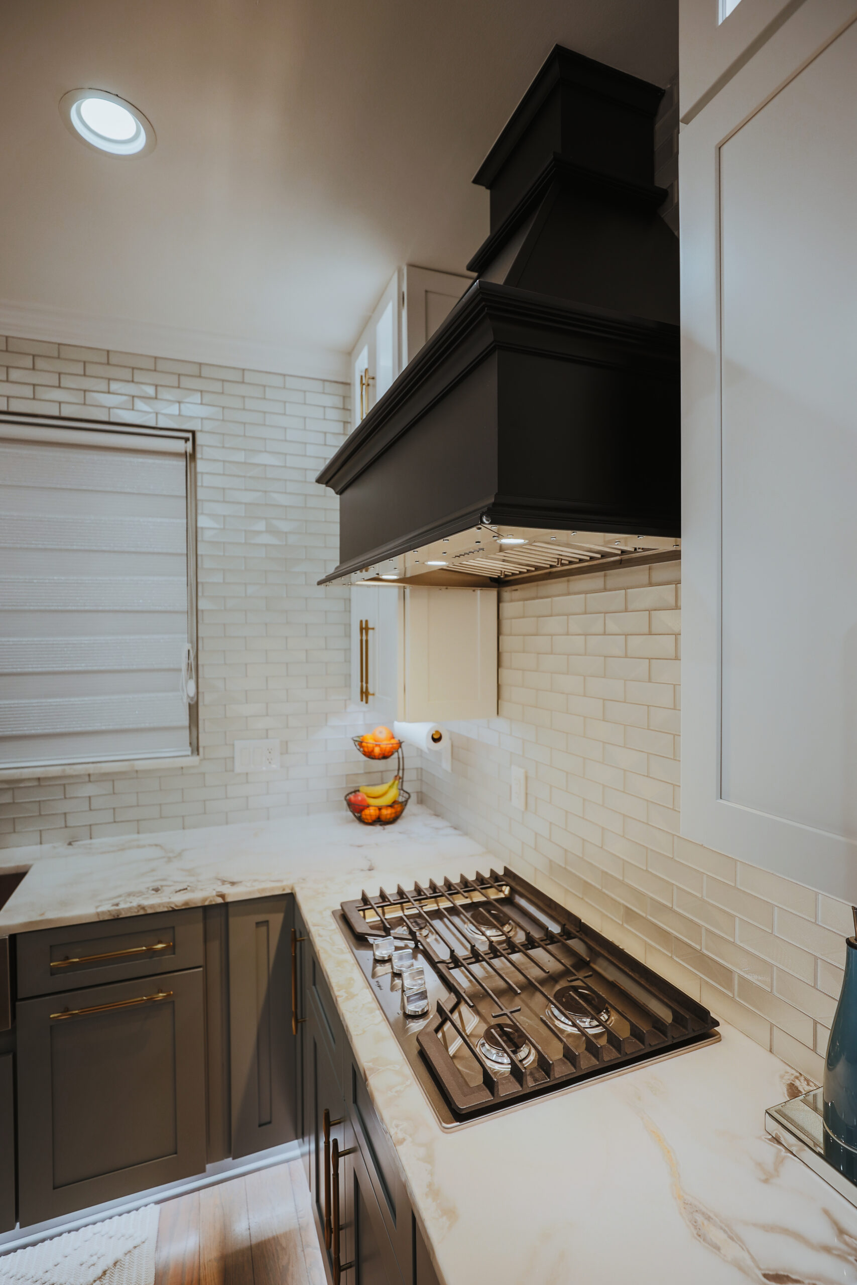 Close up of a 5 burner gas range installed in a marble kitchen countertop.