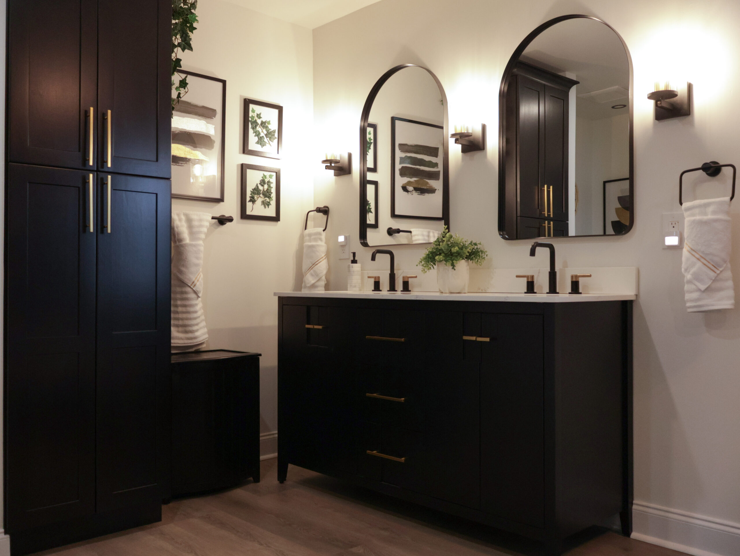 Custom black double vanity in a Dupont Circle DC home with white quartz counters, gold handles, and two arched mirrors.