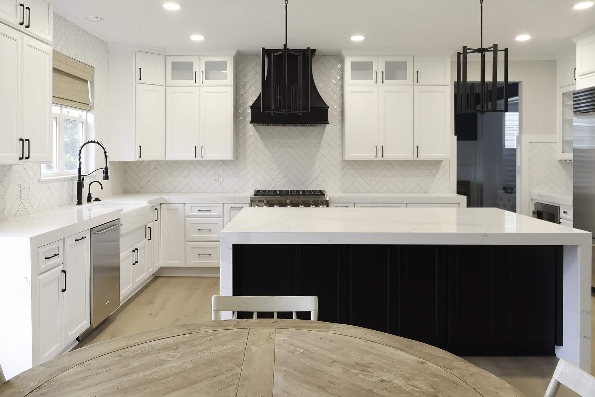 open kitchen layout with white cabinets black island quartz countertop and range hood