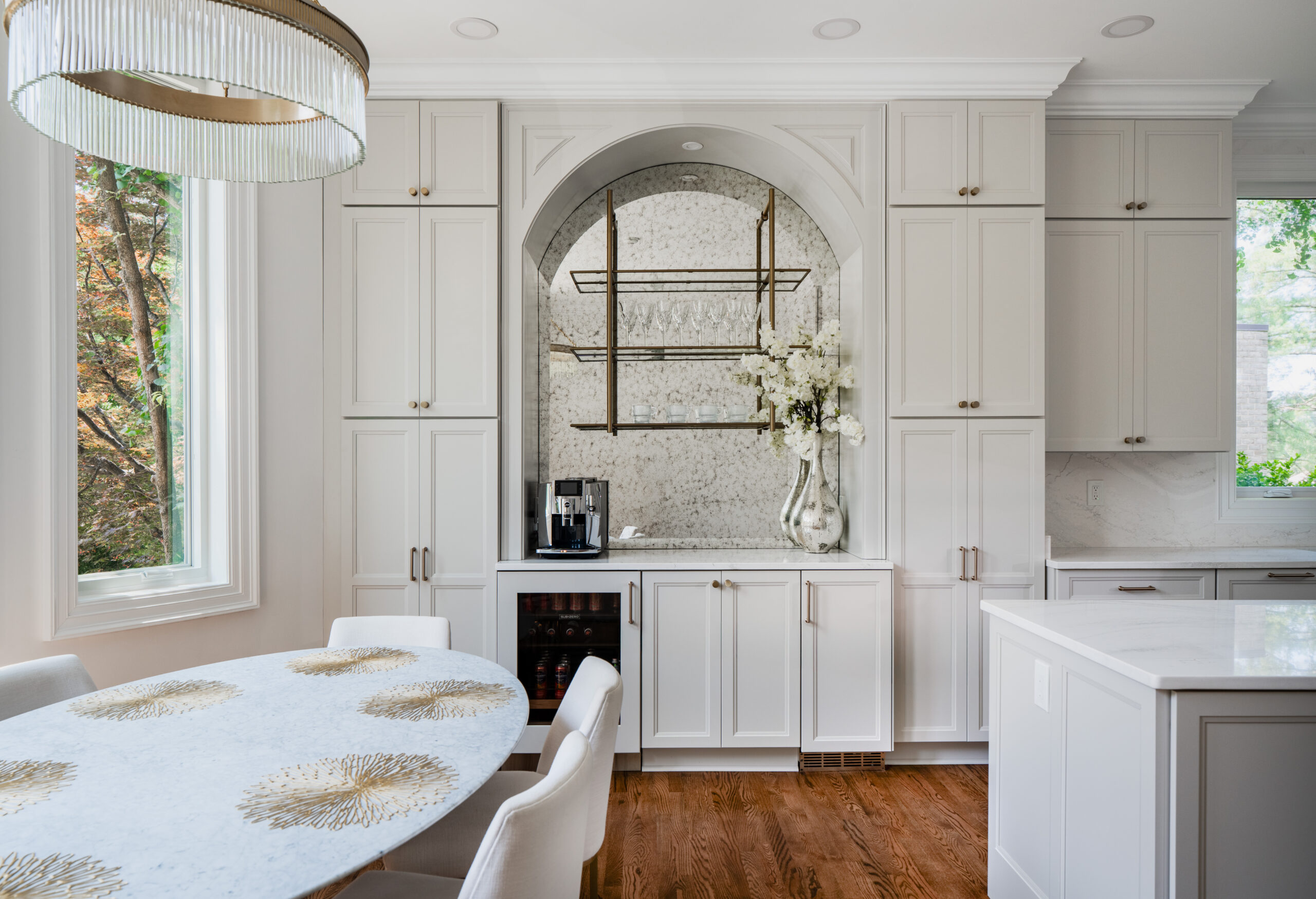 A modern arched kitchen niche featuring a marble backsplash, coffee maker, and an integrated wine cooler.