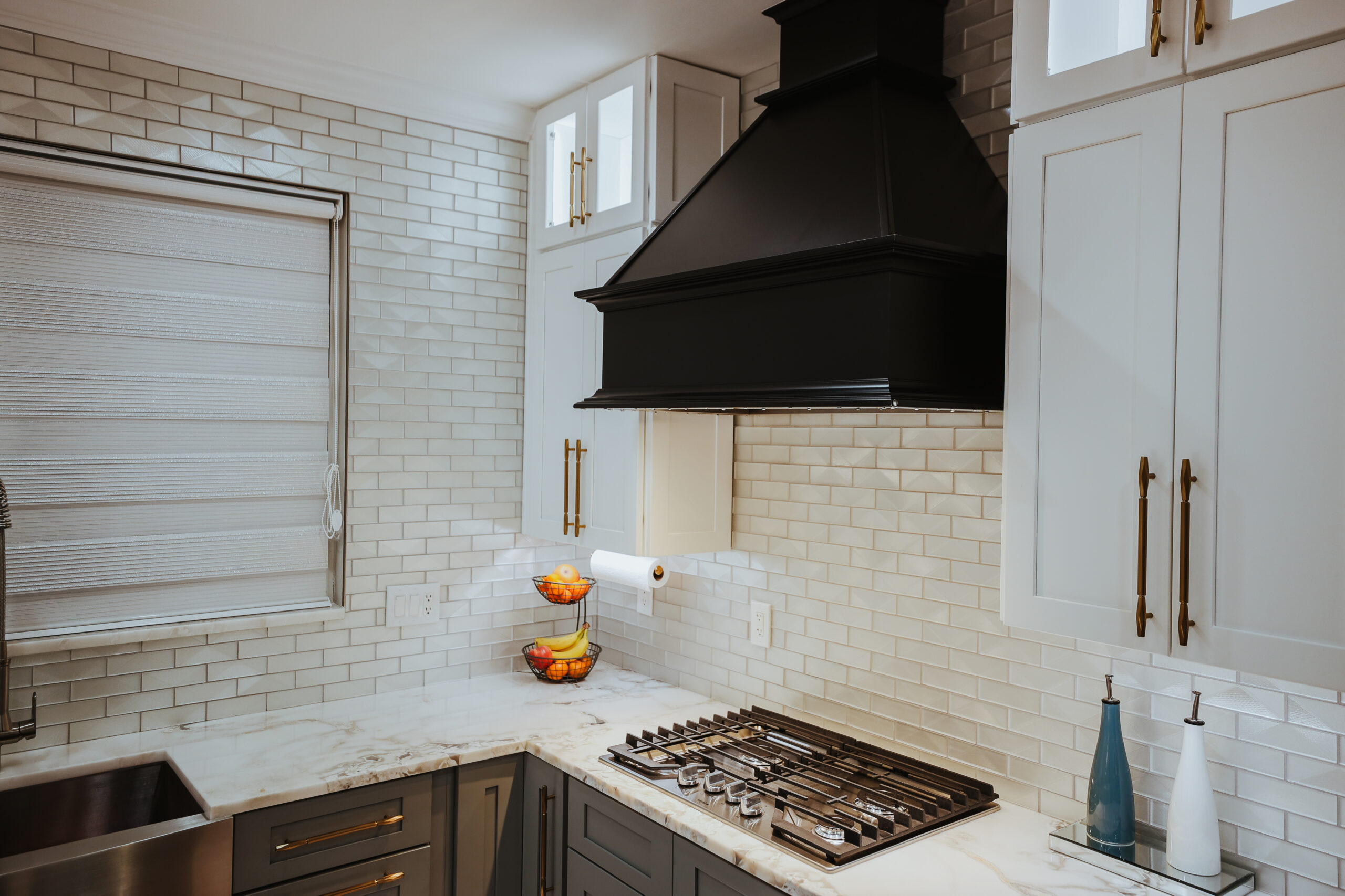 Custom black architectural vent hood mounted over a 5 burner gas range.