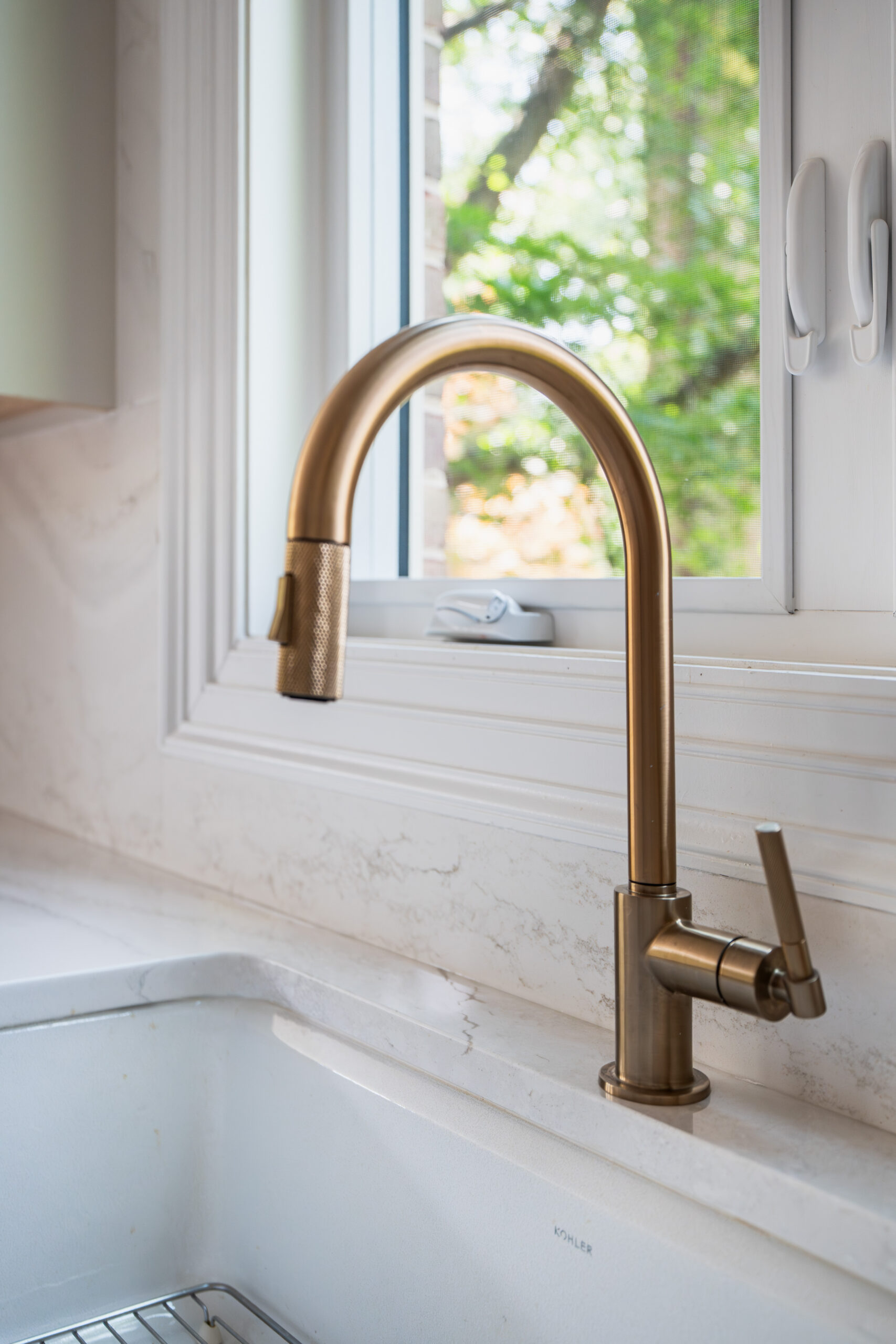 A close-up of a modern gold faucet and a clean white marble countertop.