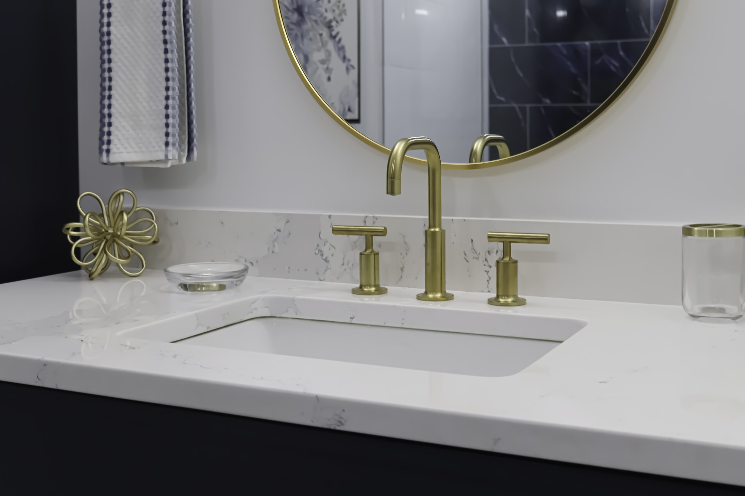 Brushed gold widespread faucet and white quartz counter.