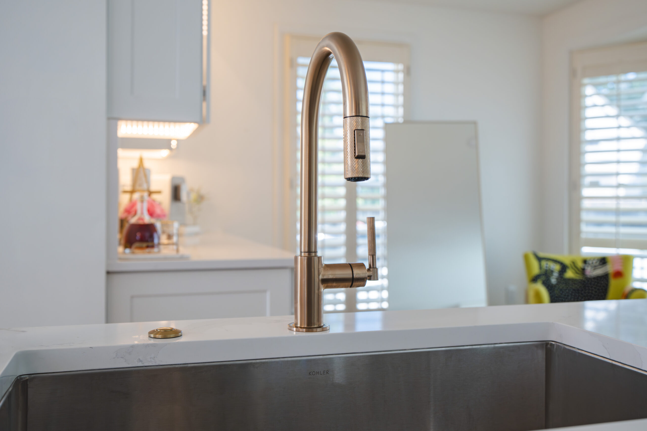 Close-up of a brushed gold gooseneck faucet on a white quartz countertop in a McLean home.