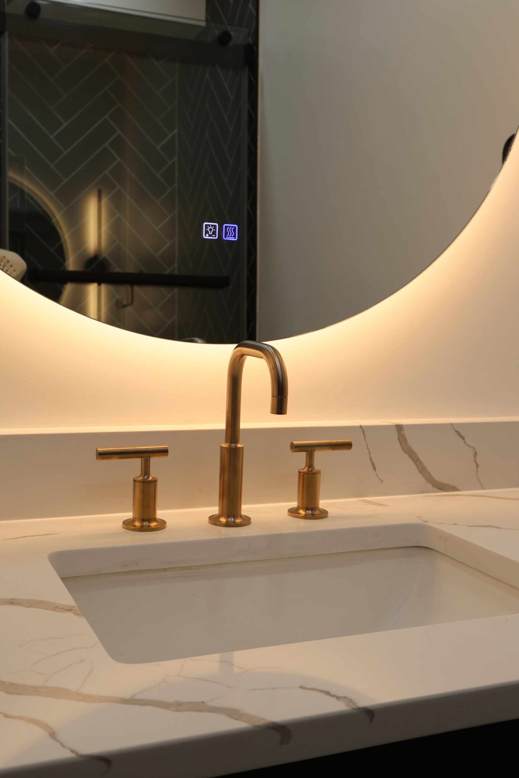 Close up of a brushed gold widespread faucet on a marble veined quartz surface.