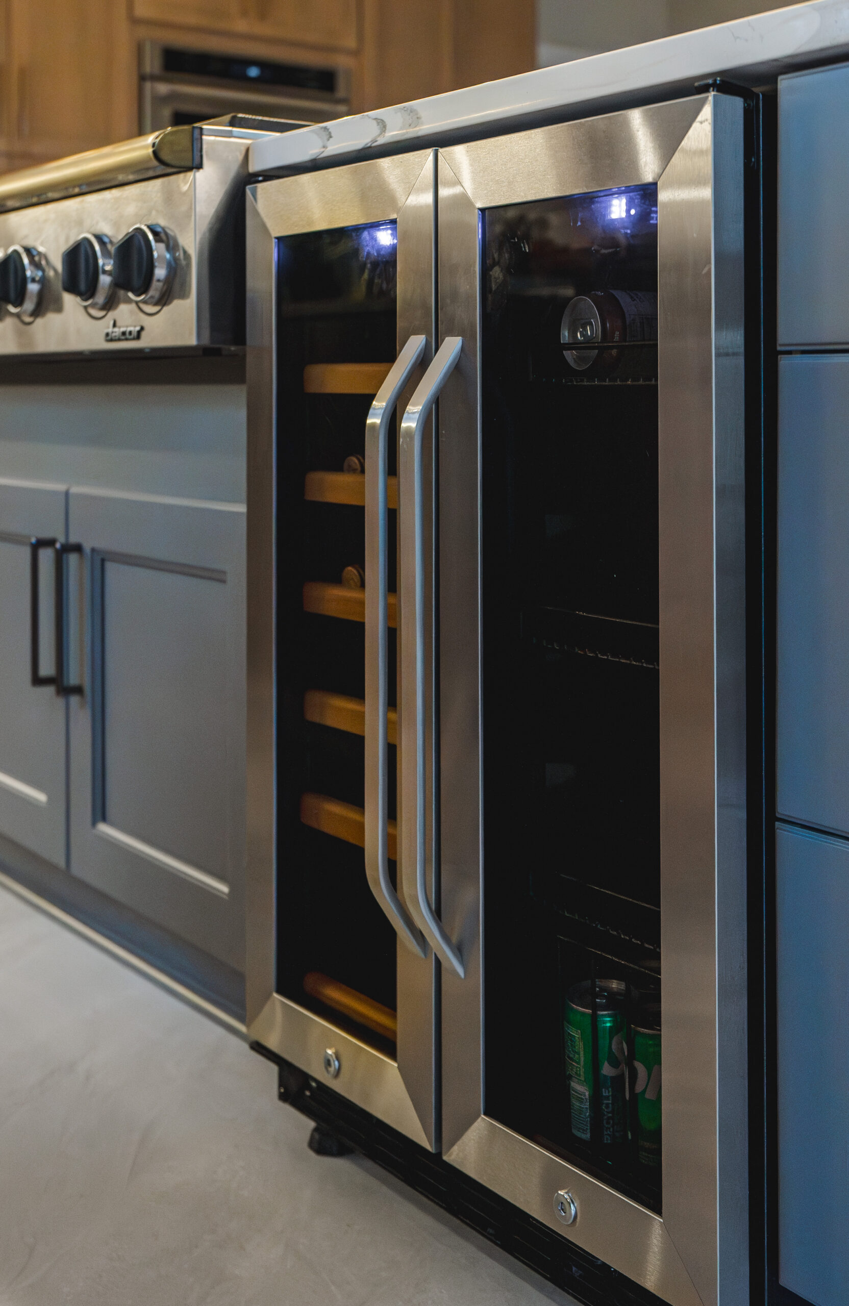 A stainless steel built-in beverage cooler and wine refrigerator installed in a dark gray kitchen island.