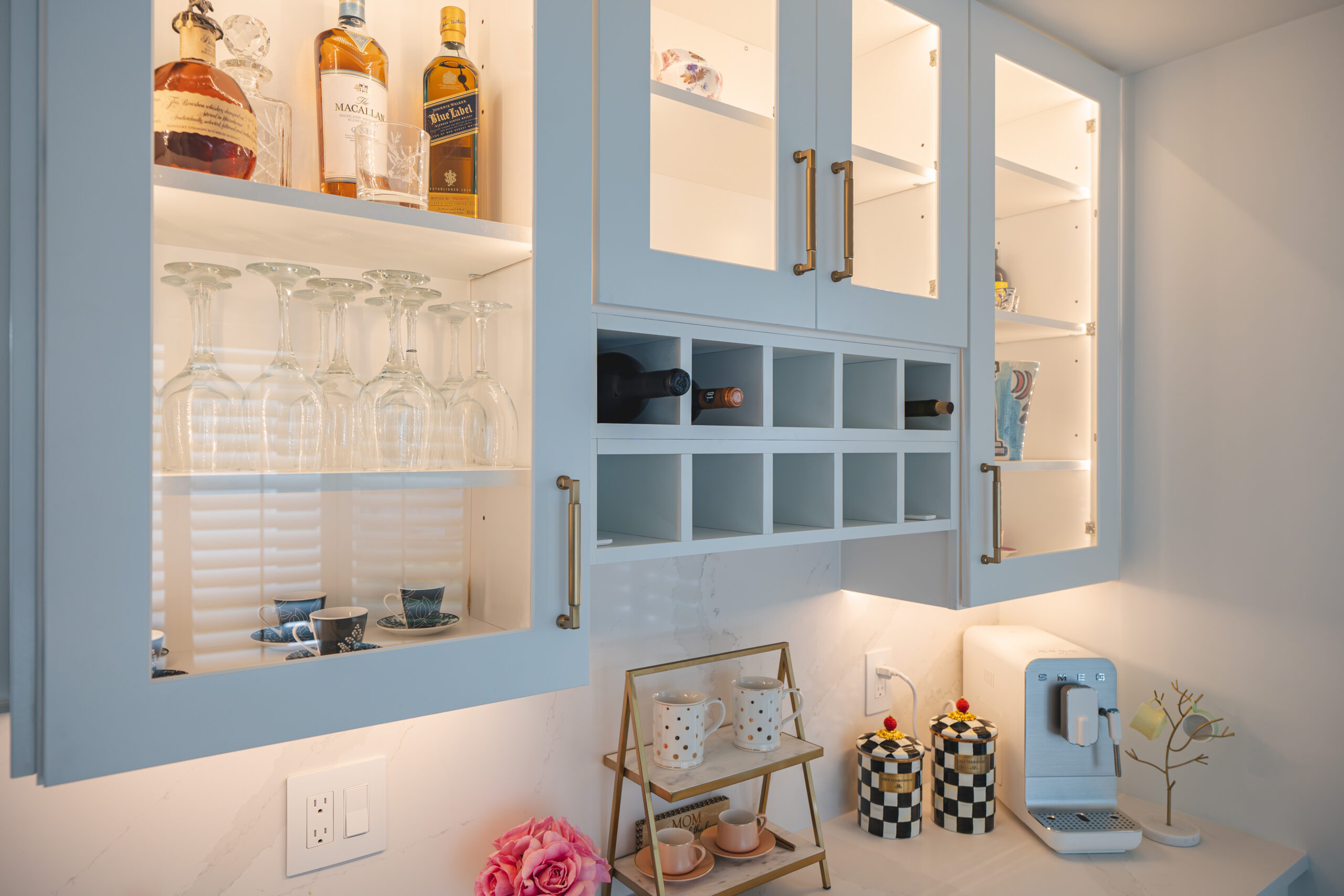 A home coffee bar with a Smeg machine, white shaker cabinets, and interior cabinet lighting.