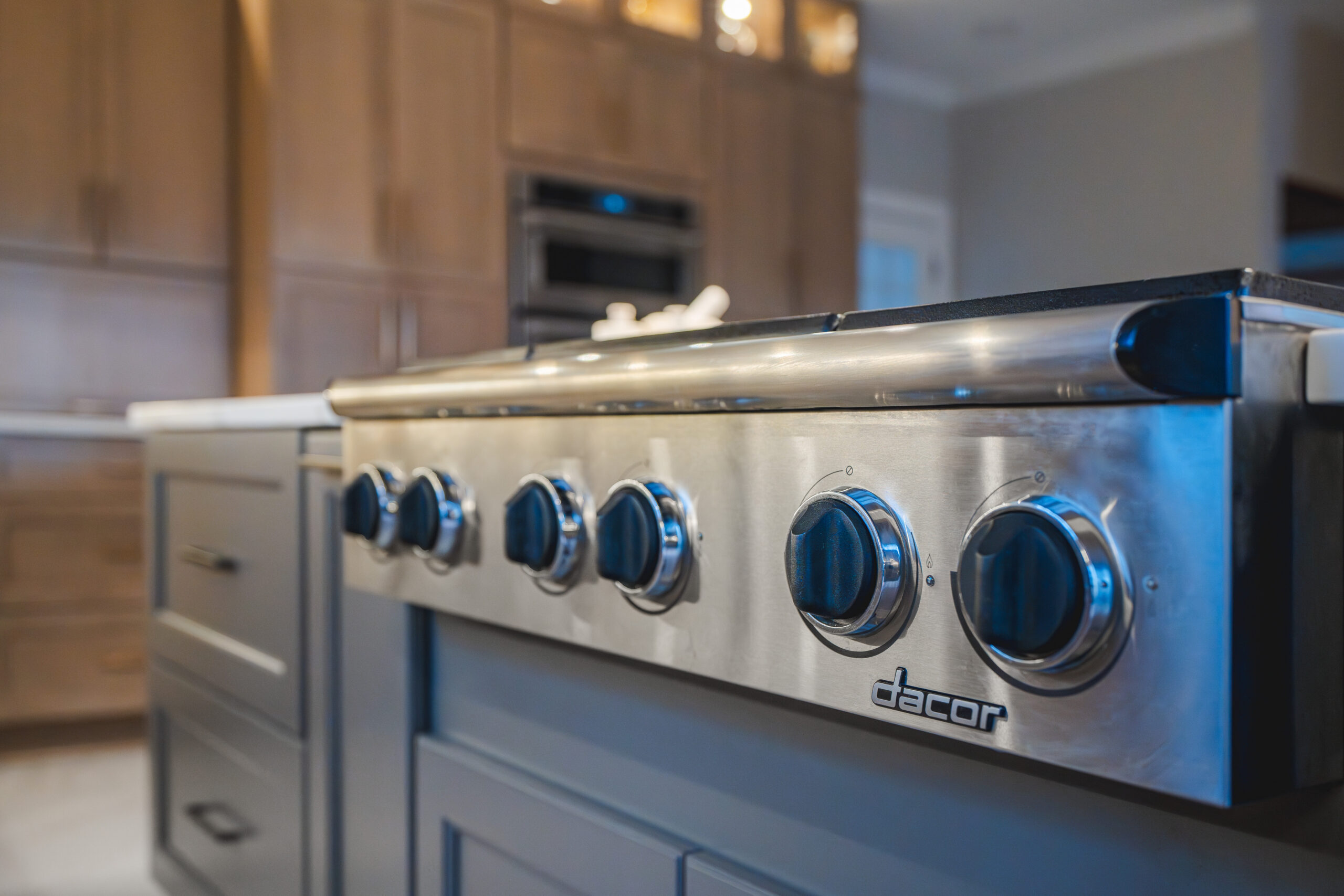 Close-up of a professional-grade Dacor gas cooktop installed on a charcoal gray kitchen island with stainless steel controls.