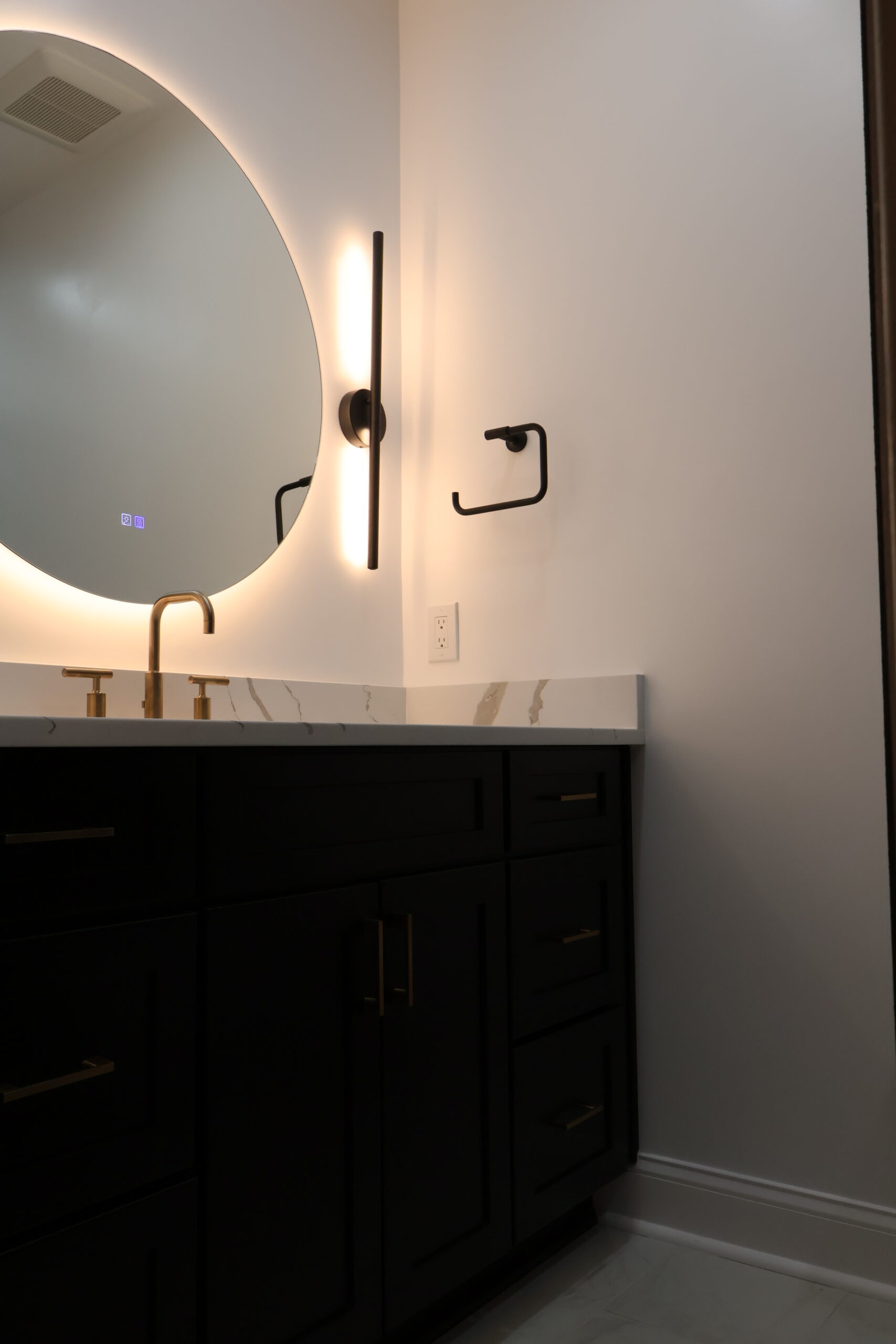 Modern dark wood vanity with a circular backlit LED mirror for a Bathroom remodeling