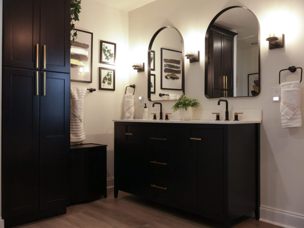 Custom black double vanity with gold hardware and elegant arched mirrors in a professionally renovated Washington D.C. bathroom.