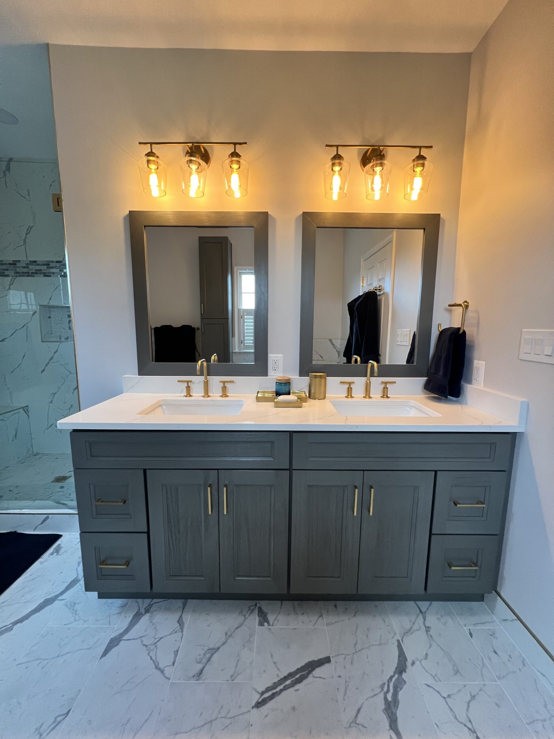 Gray shaker double vanity with brushed gold faucets for a Bathroom renovation.