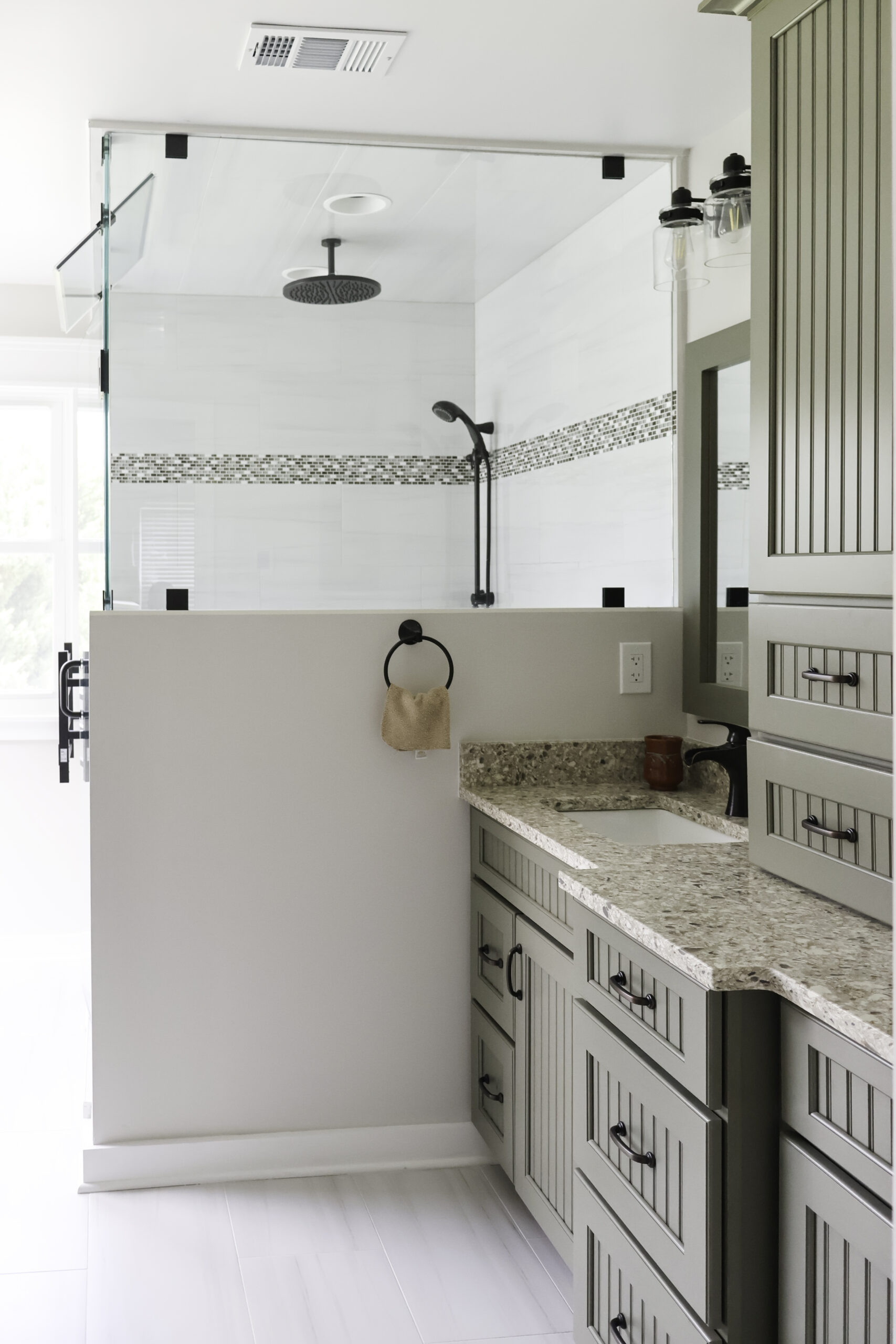 View of a double sink vanity next to a half-wall glass shower enclosure.