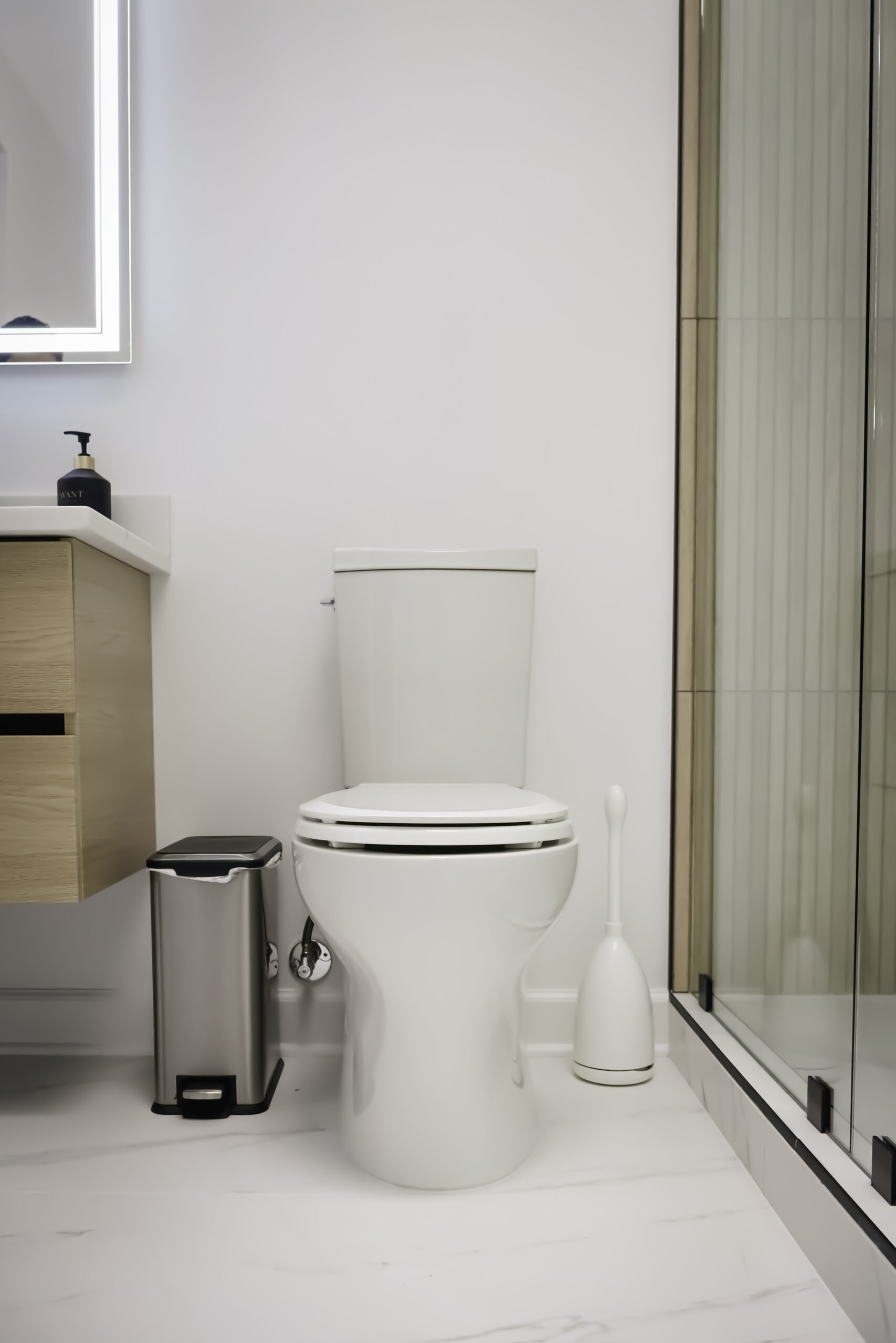 Modern floating oak vanity and high efficiency white toilet.