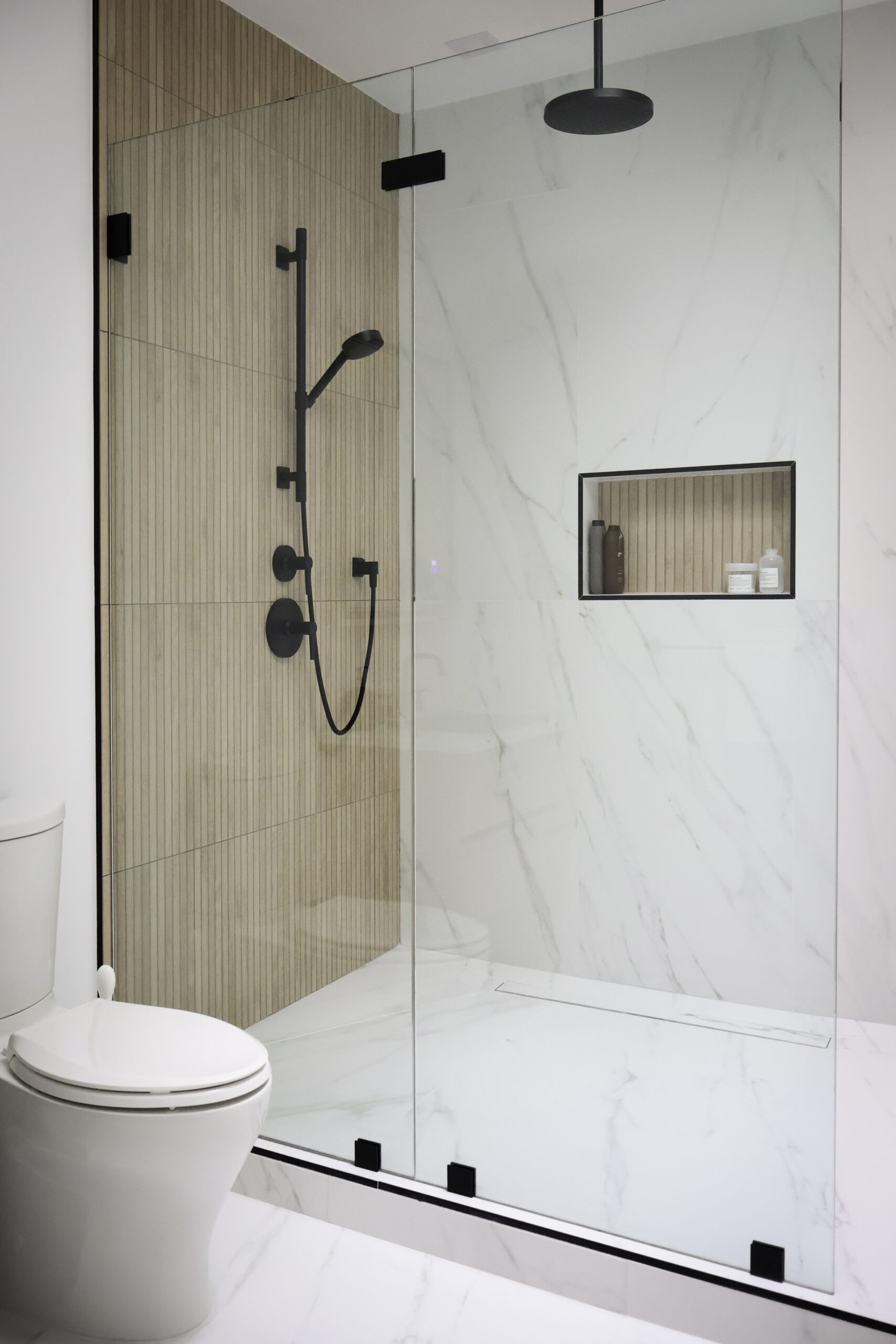 Frameless glass shower door with matte black hinges and handle.