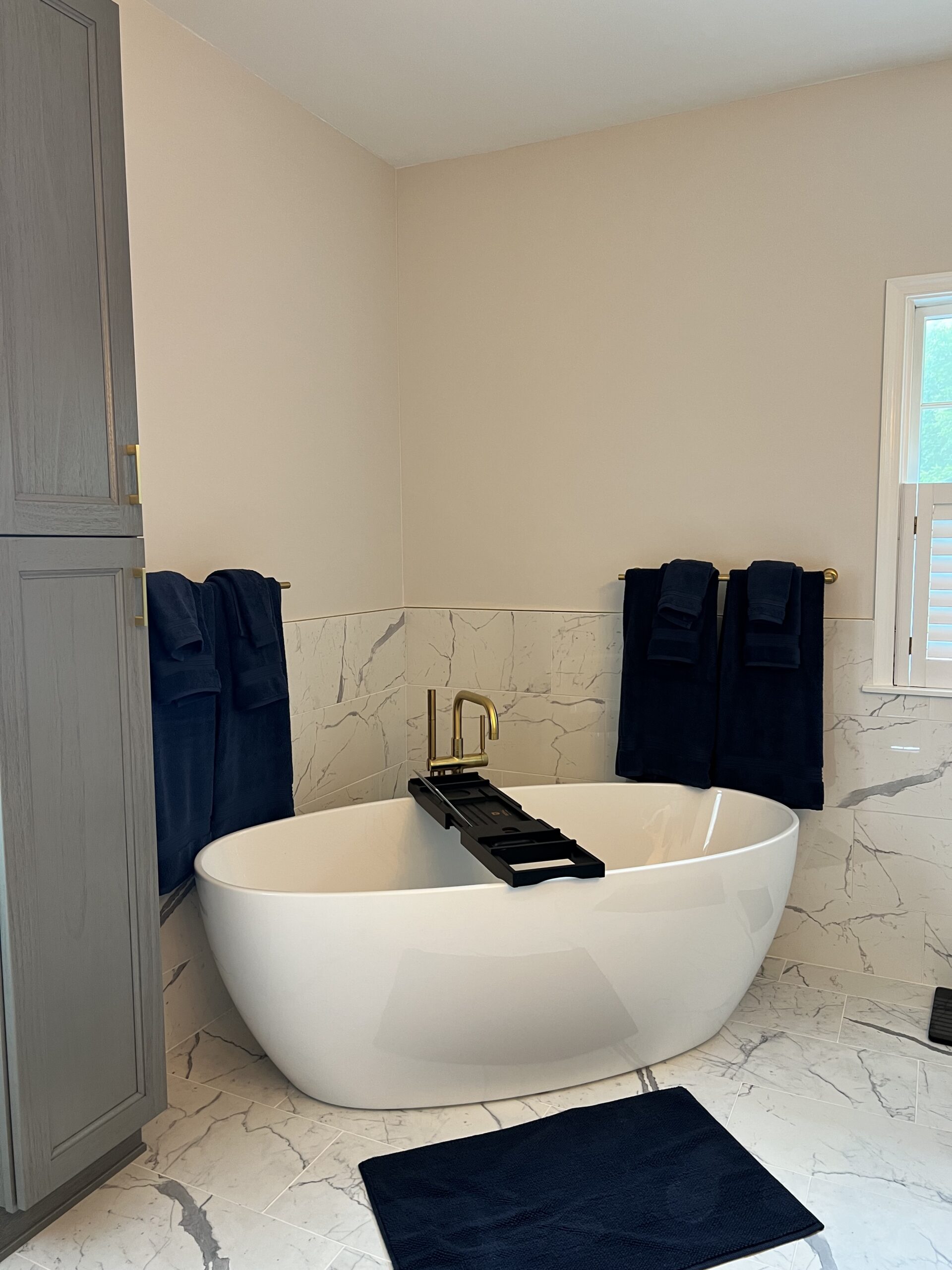 White freestanding soaking tub with a floor-mounted gold filler.