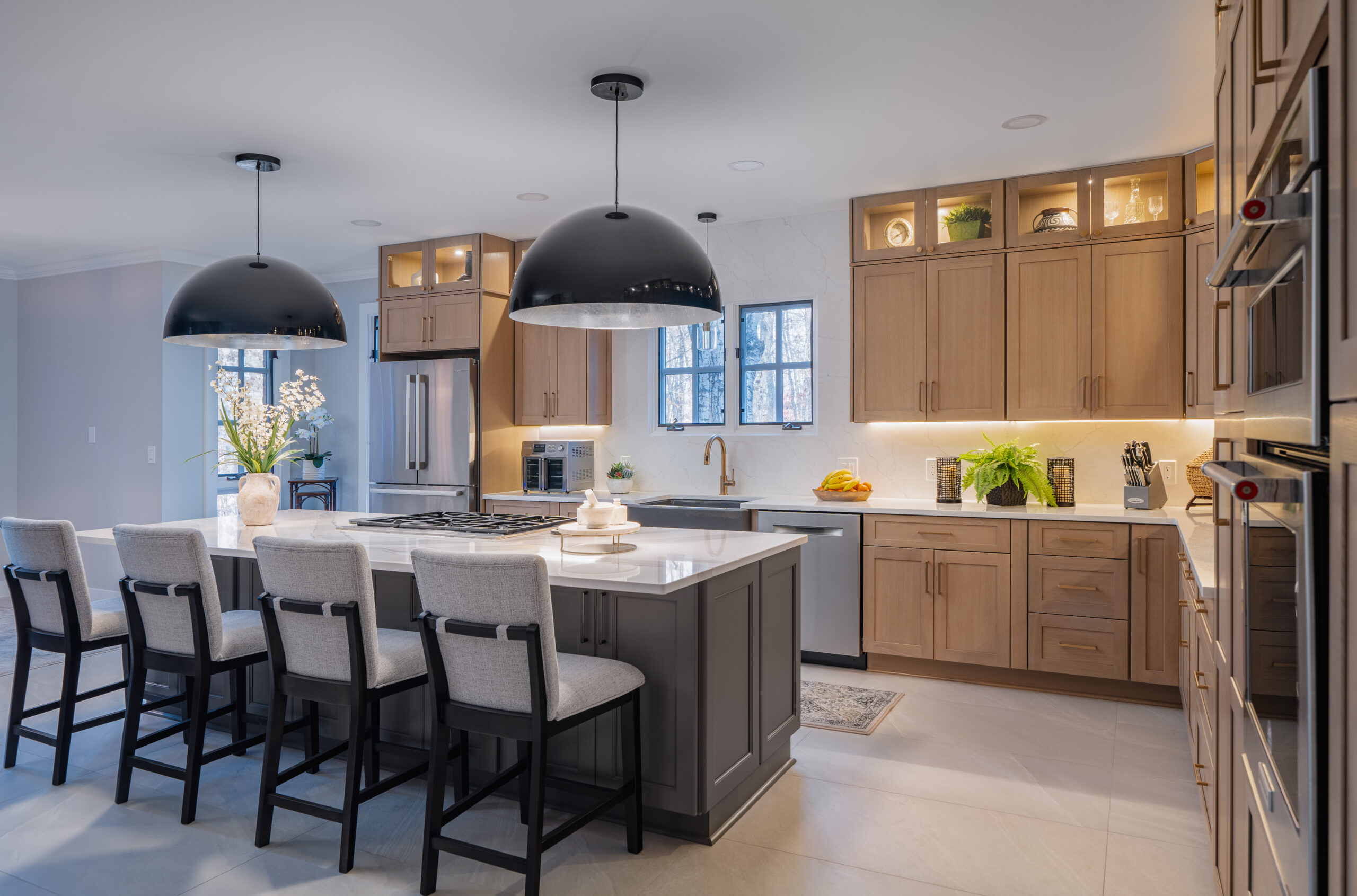 Large charcoal gray kitchen island with white quartz countertop and oversized matte black dome pendant lights.