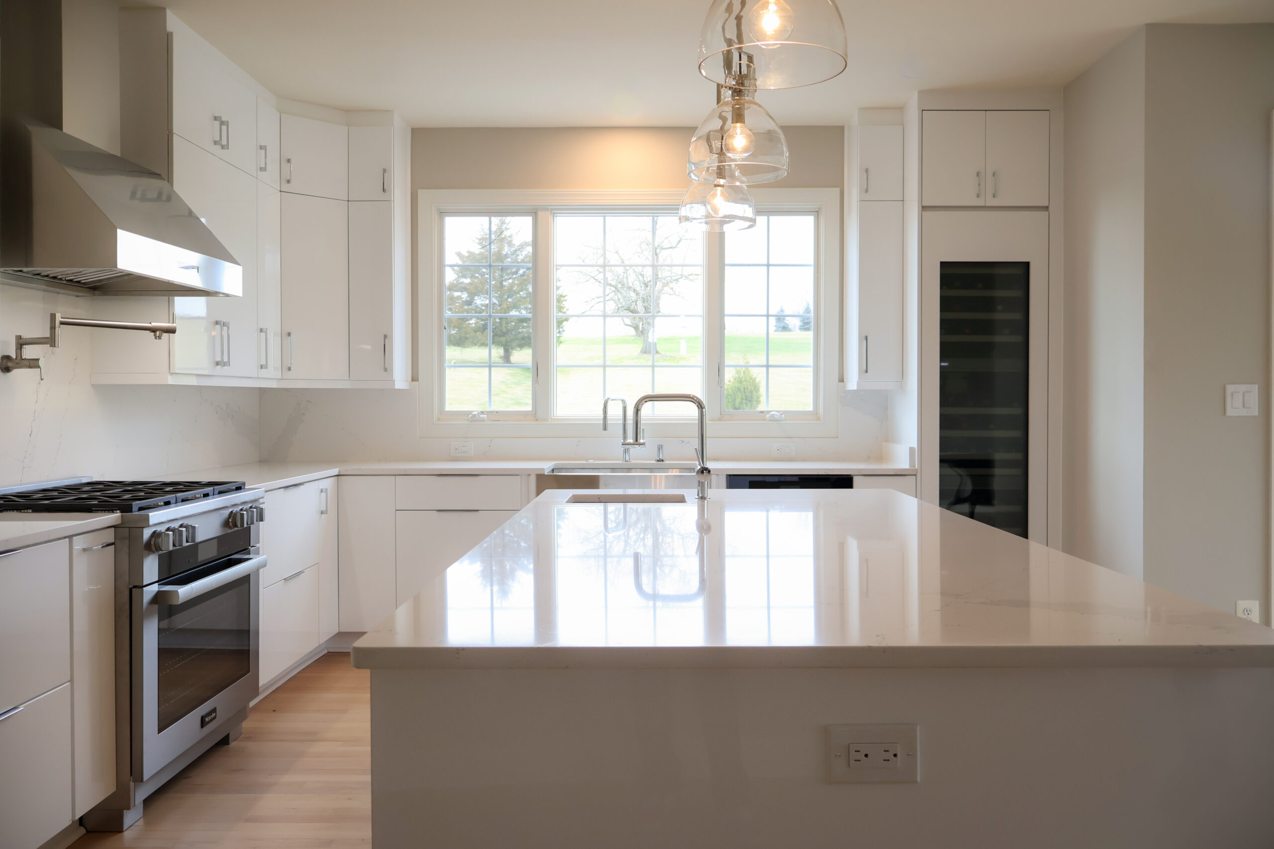 Tall glass front wine cooler integrated into a modern high gloss cabinet wall.