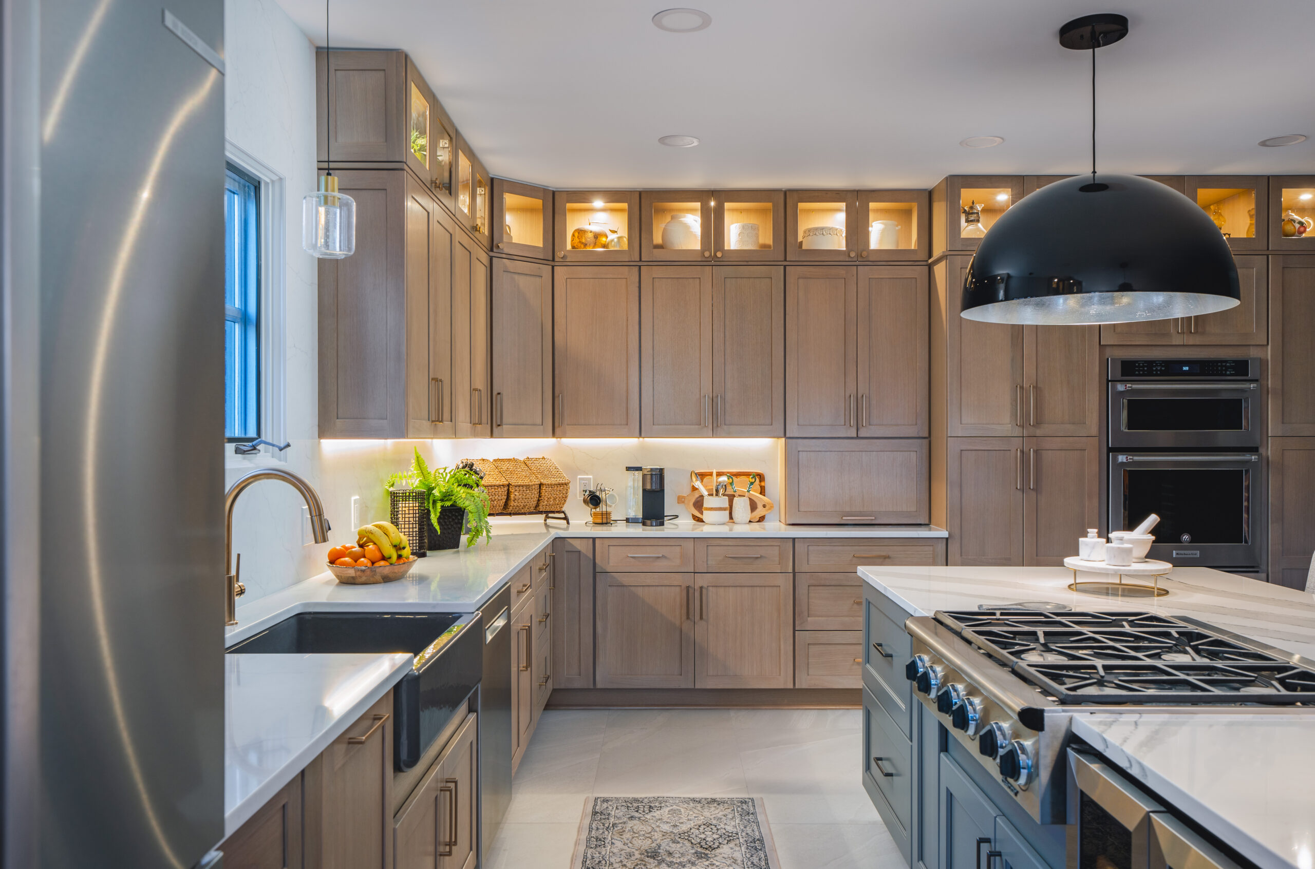 Detail shot of custom natural wood kitchen drawers and a white marble-veined quartz countertop with a gas cooktop.