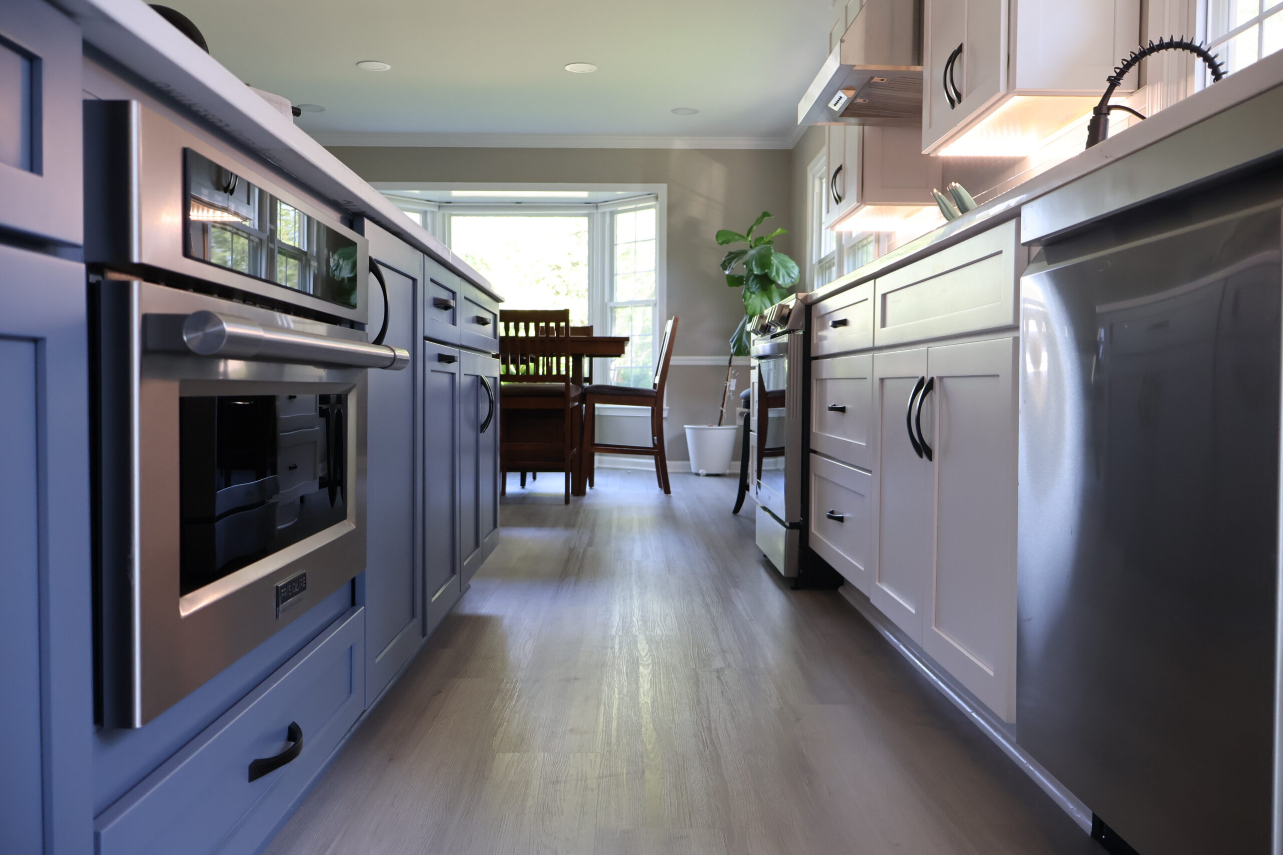 Two-tone shaker cabinetry and wide-plank flooring for a Kitchen remodeling.