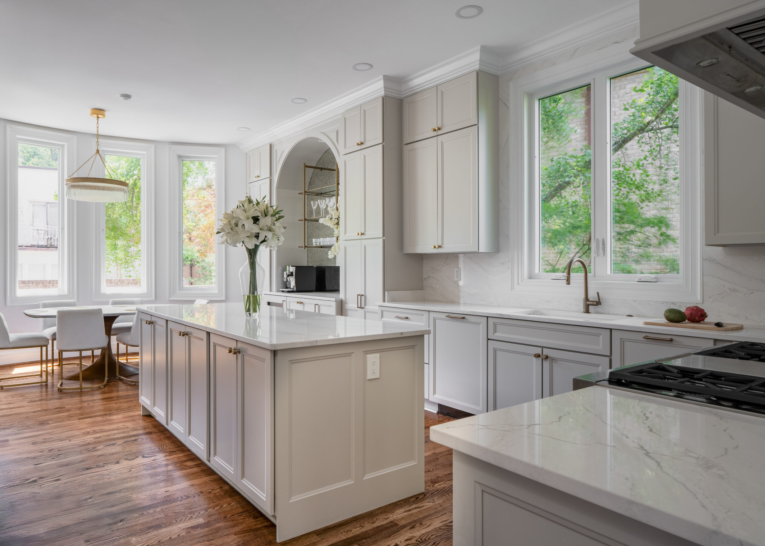 A view looking from the kitchen island toward the bright dining area with hardwood floors.