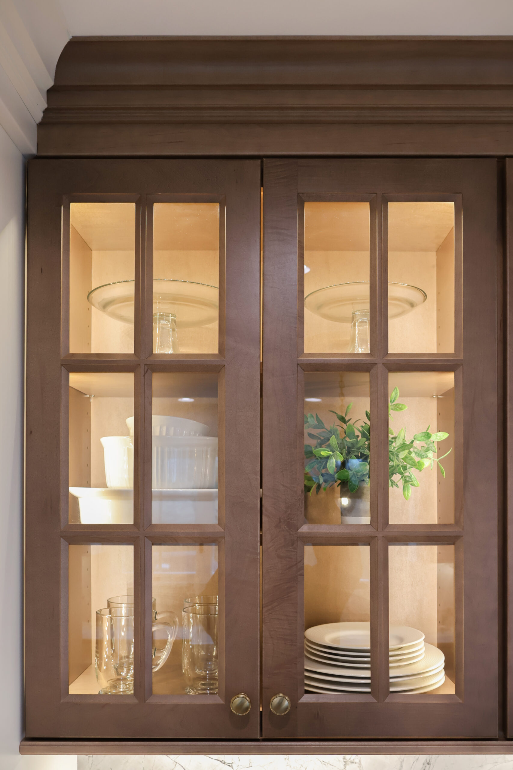 Detail of dark wood upper cabinets in a Georgetown DC kitchen with glass doors and internal LED lighting for displaying fine china.