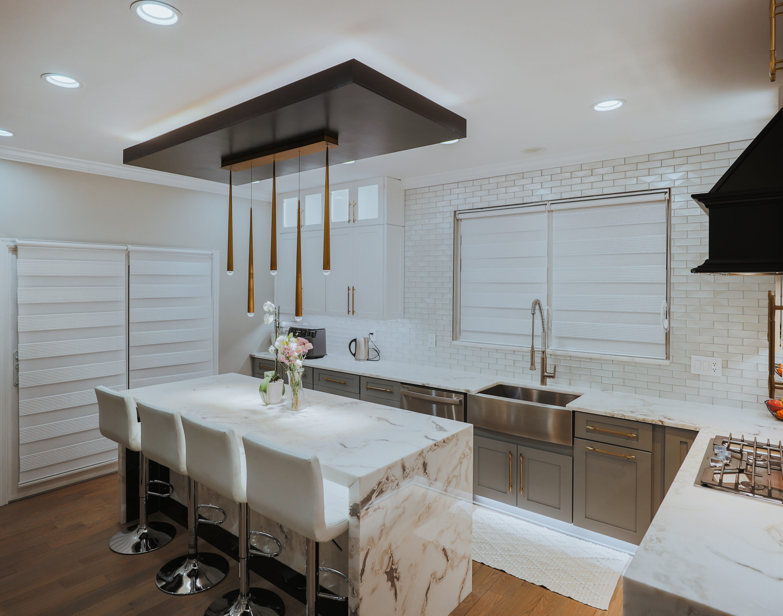 Large marble waterfall kitchen island with gold designer pendant lights.