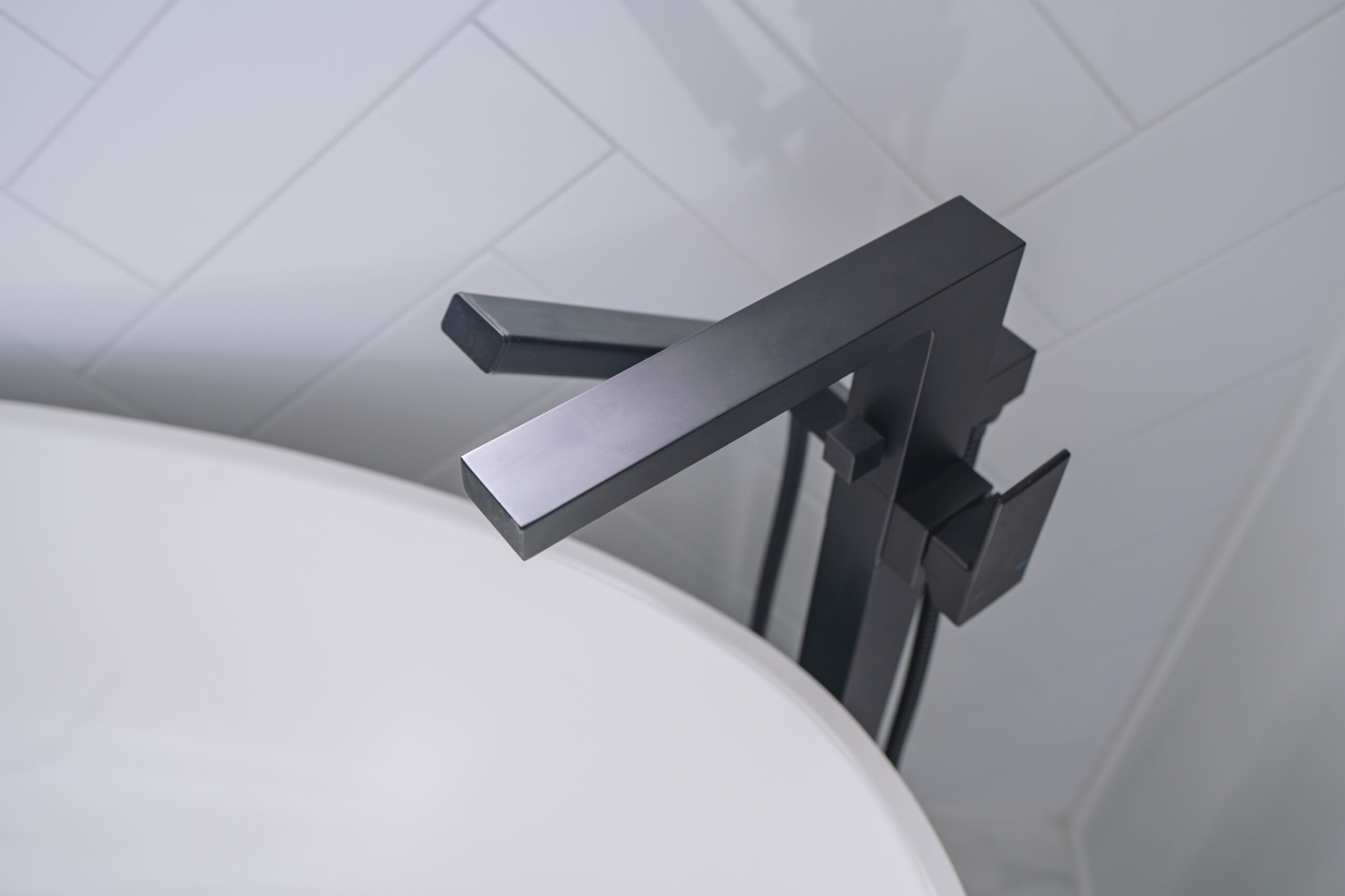 A close-up, top-down view of a matte black square faucet on a white marble vanity top.