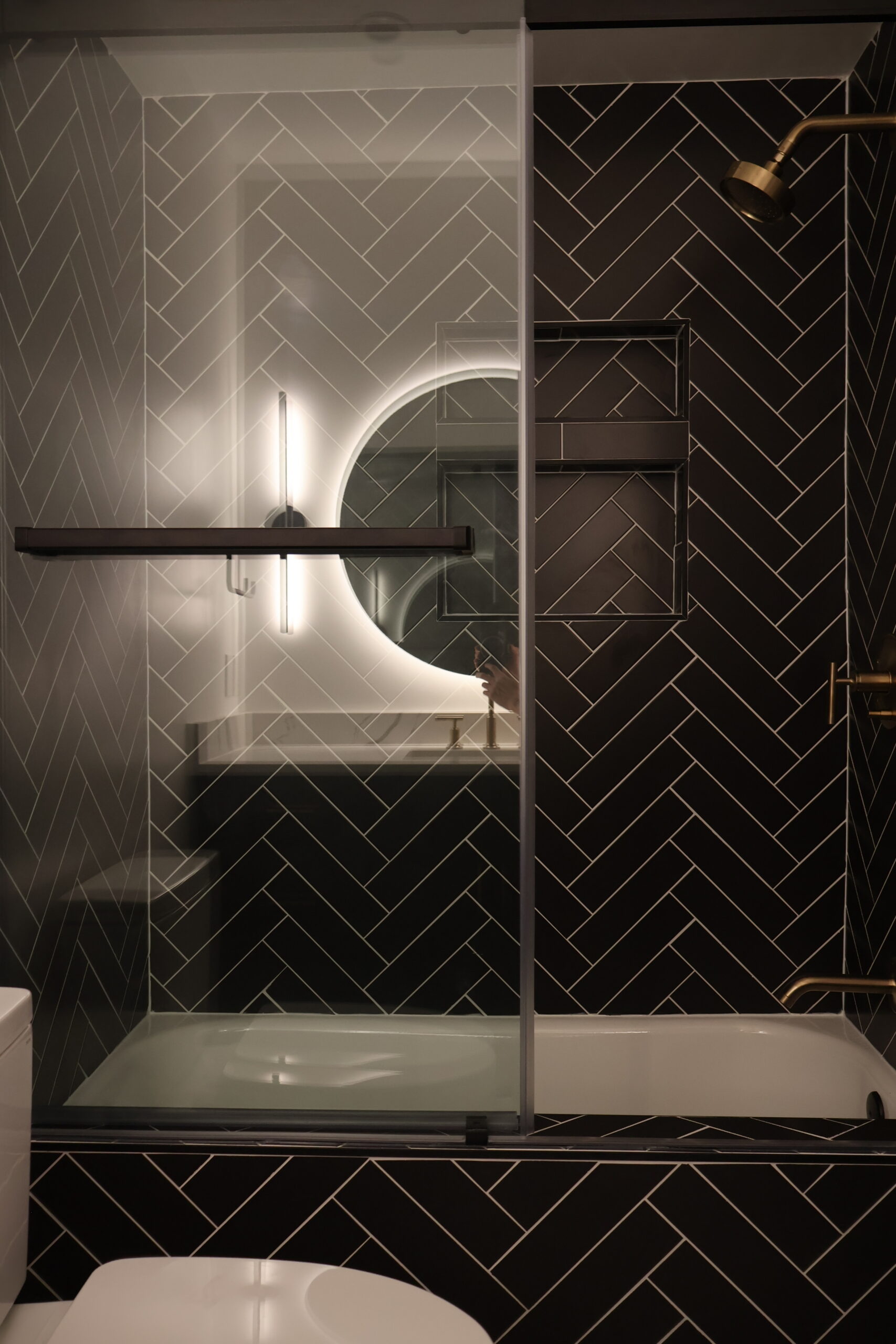 Matte black stick wall sconce and matching geometric towel ring.