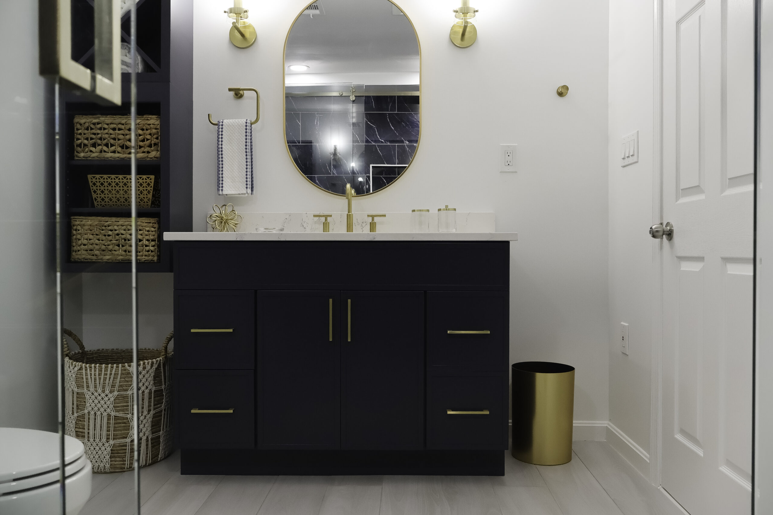 Modern navy blue double vanity with gold hardware and oval mirror.