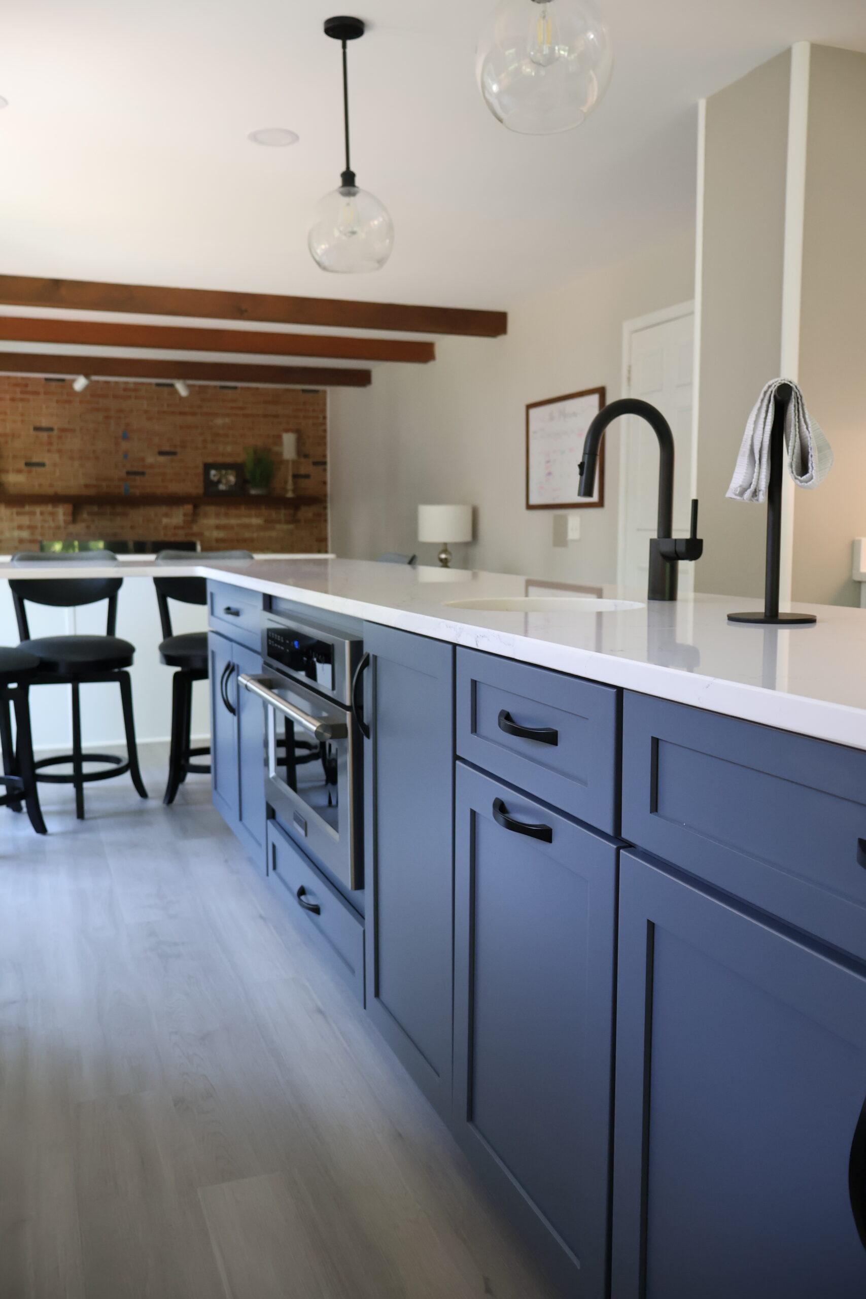 Large kitchen island looking toward a living area with exposed wood beams.