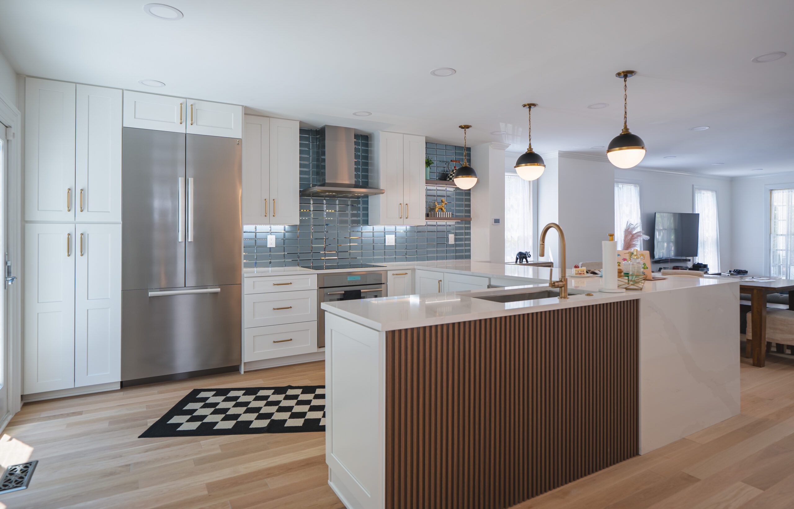 A full view of the renovated U-shaped kitchen showing the flow into the living room and natural light from large windows.