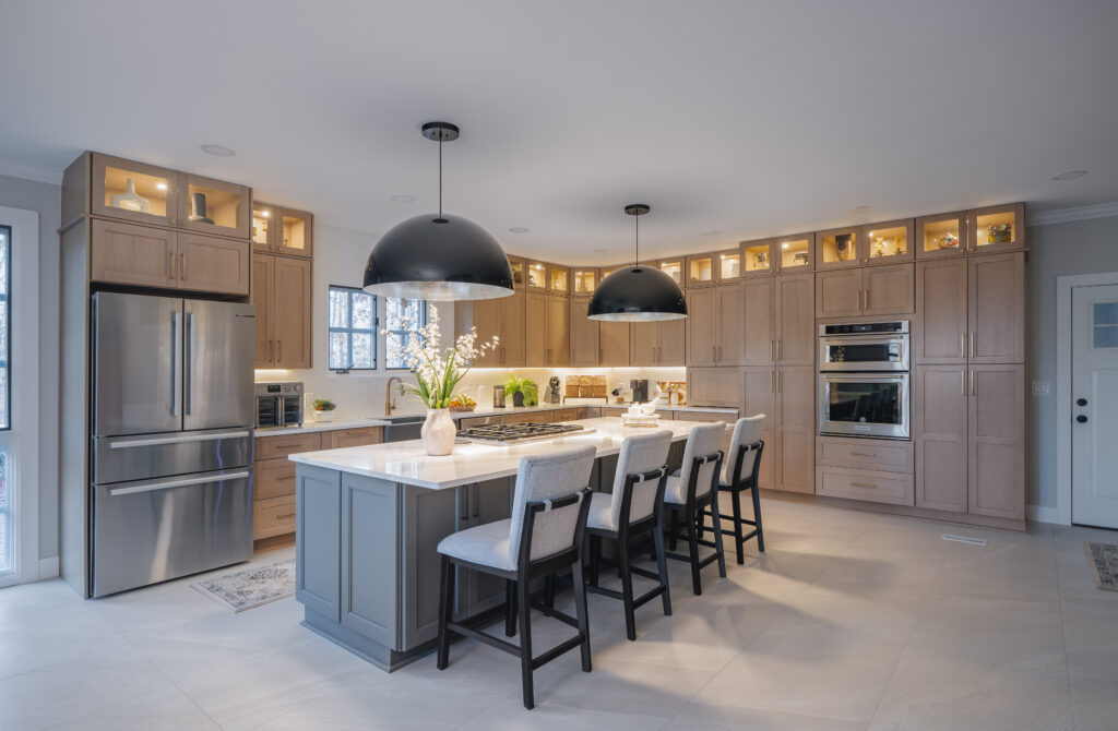 Full view of an open-concept kitchen renovation featuring wood cabinets, a gray center island, and high-end stainless steel appliances.