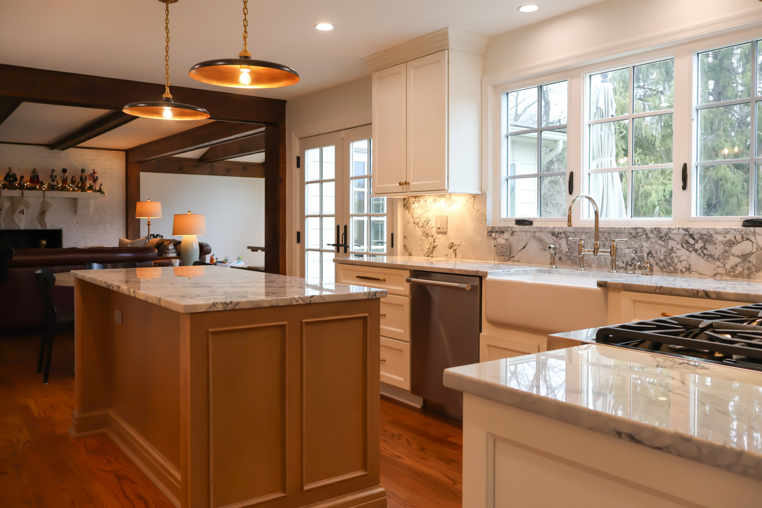 View from a modern Georgetown DC kitchen looking into a living room with exposed wood ceiling beams and a white brick fireplace.