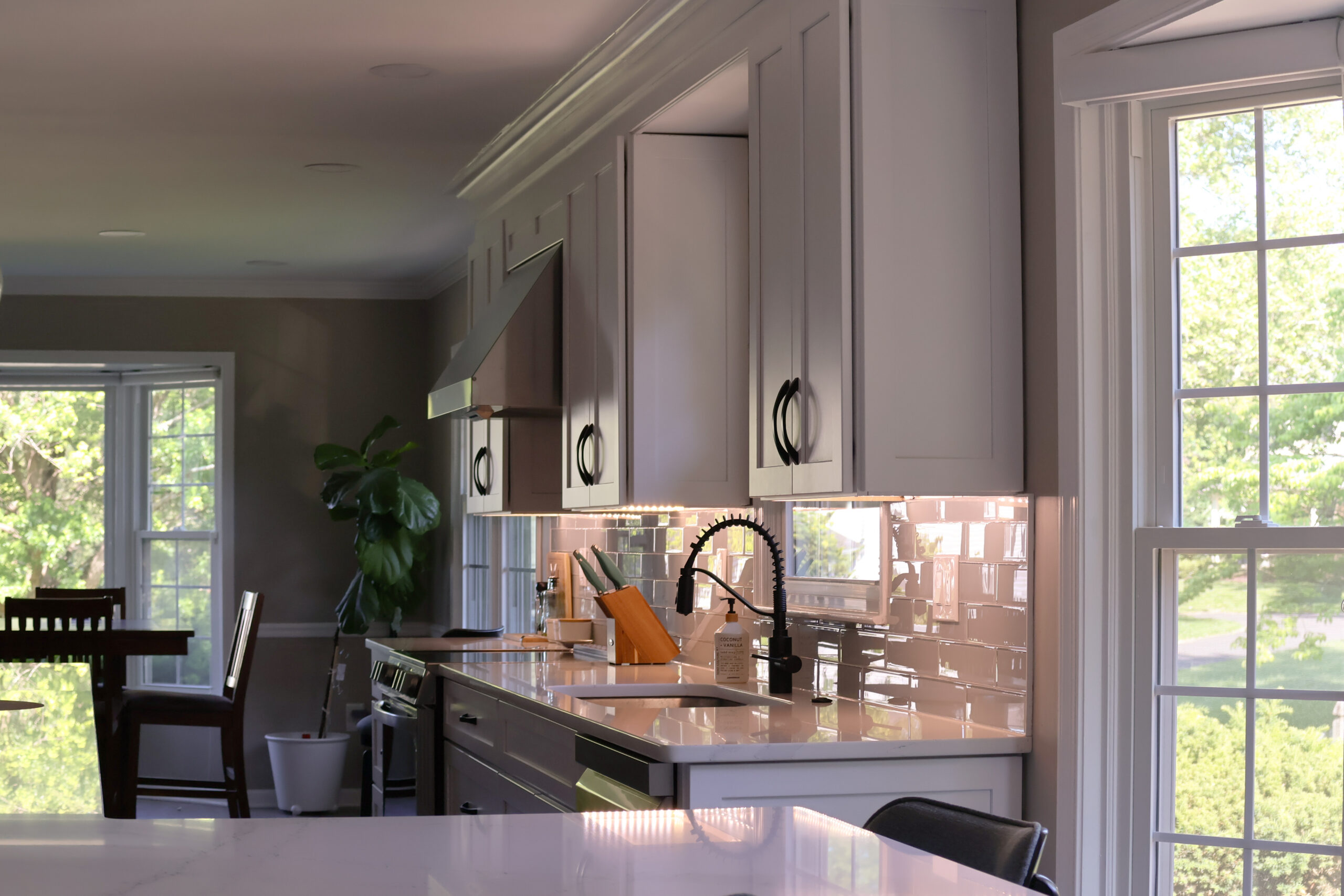 Matte black spring neck faucet and glossy white subway tile backsplash.