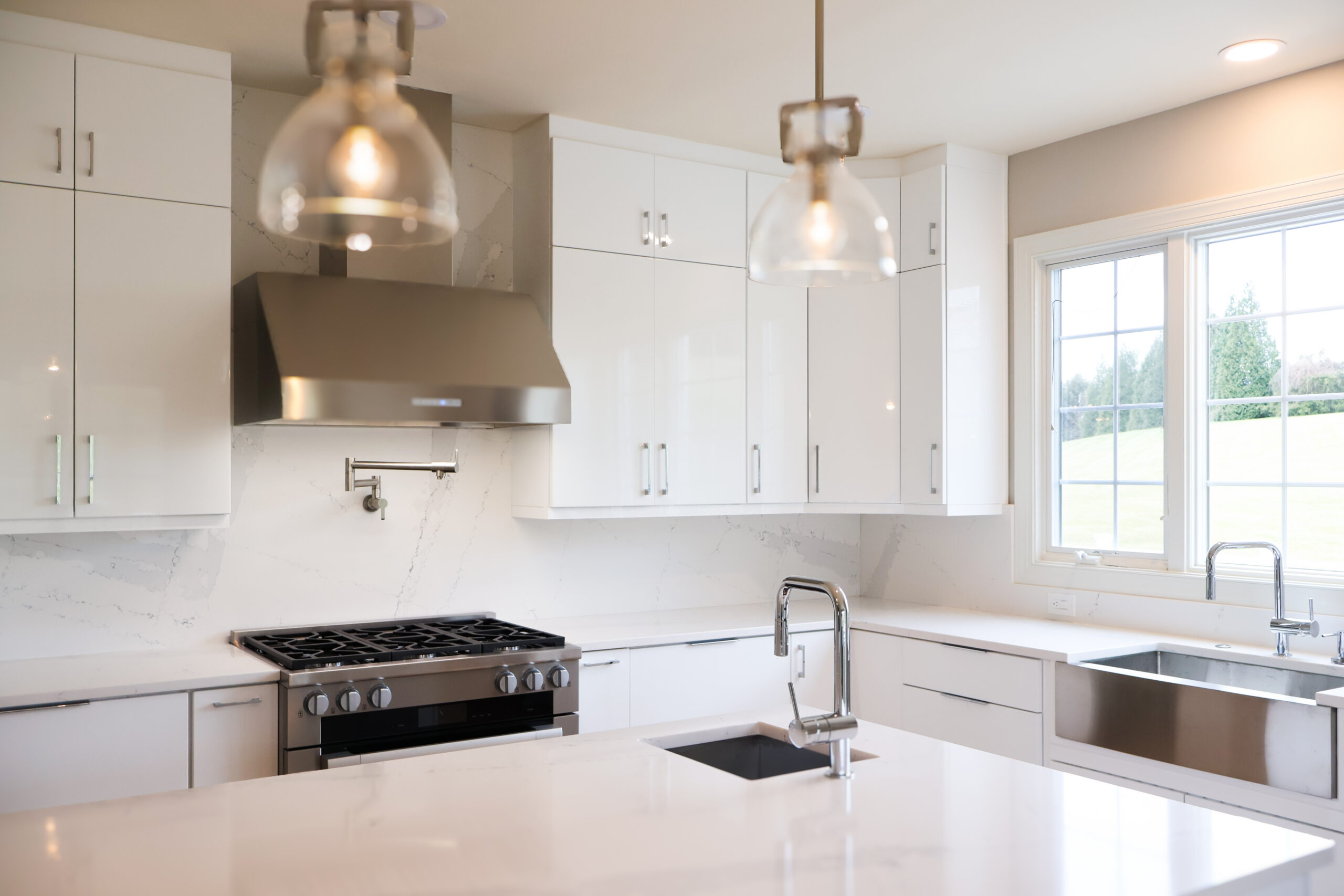 Large quartz kitchen island with an integrated prep sink and glass pendant lights.