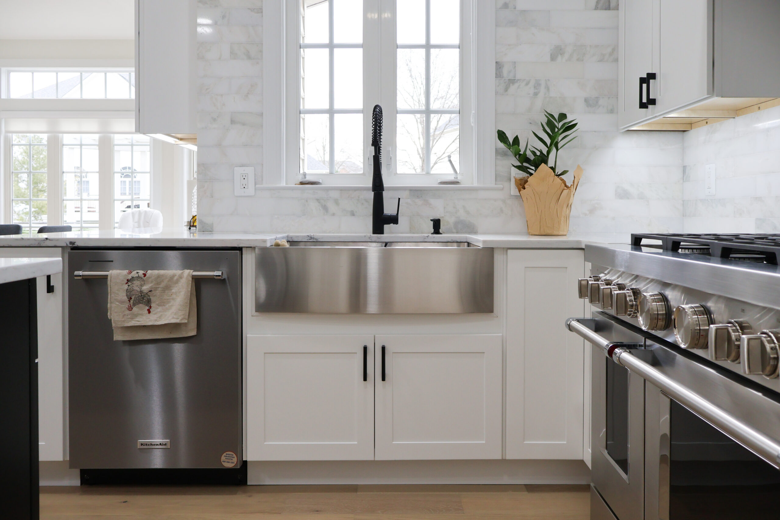Stylish kitchen sink area with a stainless steel apron-front sink and high-arch faucet.