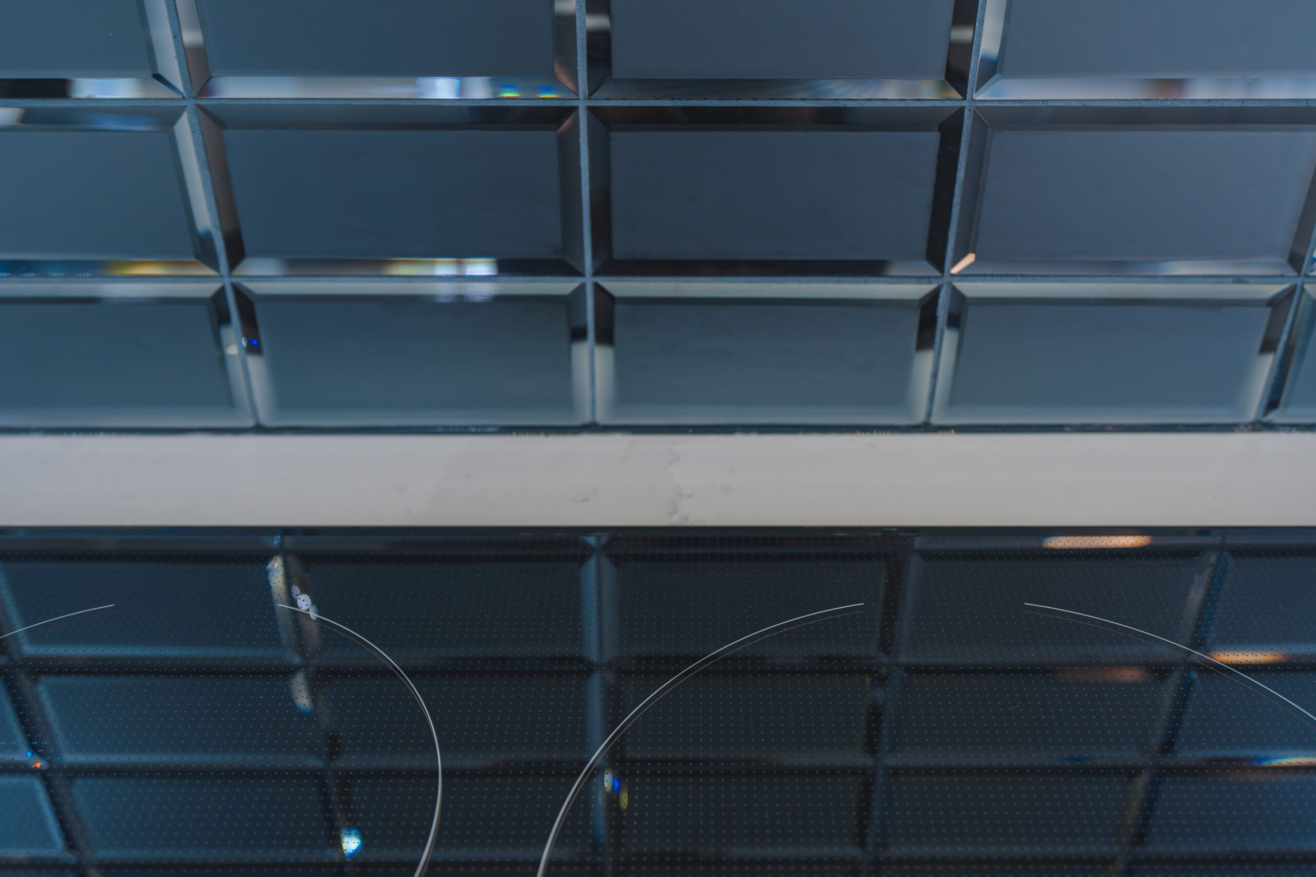 A detailed view of high-gloss teal glass subway tiles meeting a white quartz countertop.