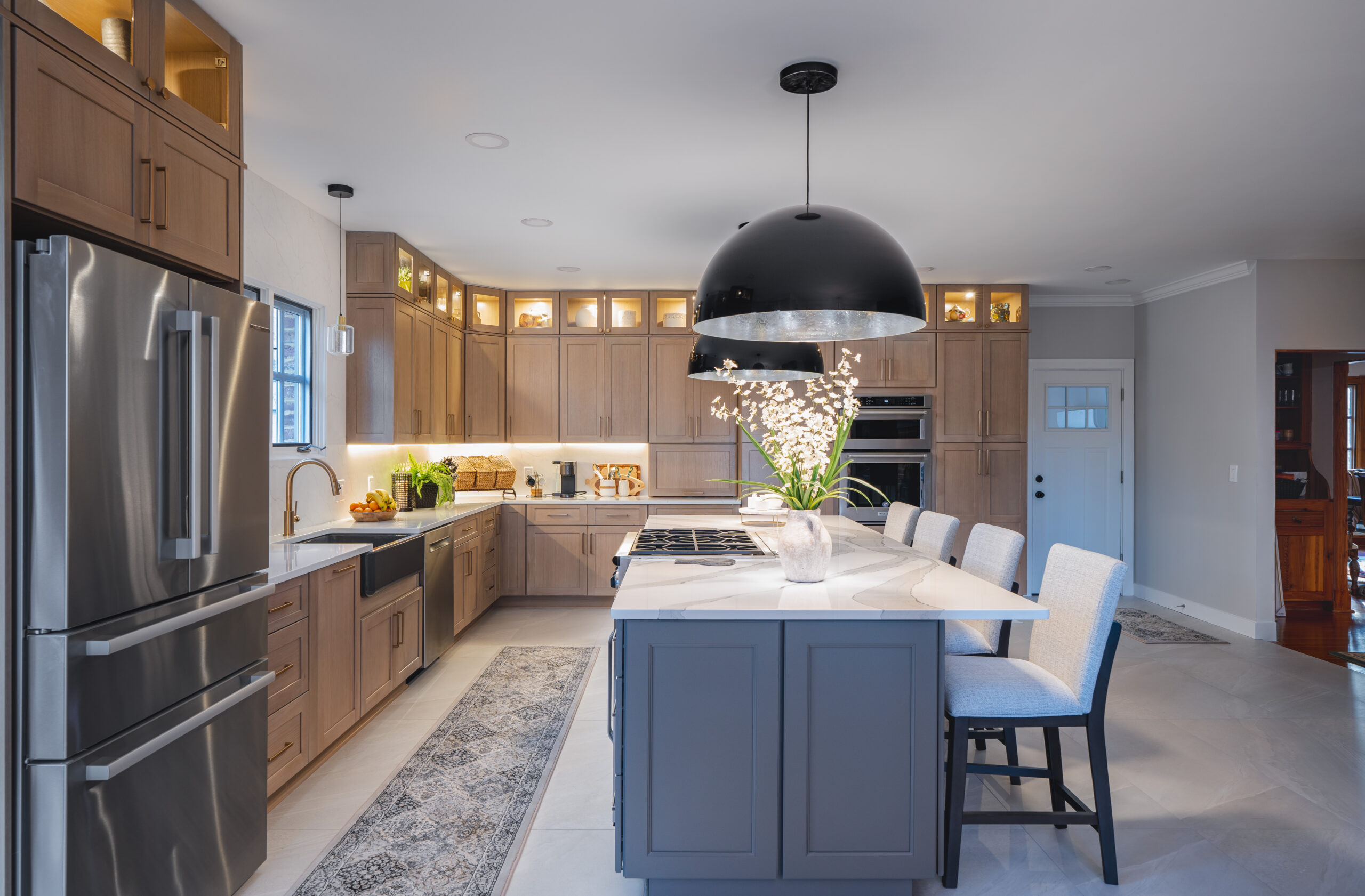 A wide perspective of a transitional kitchen layout showing the sink area, kitchen island, and hardwood-style flooring.