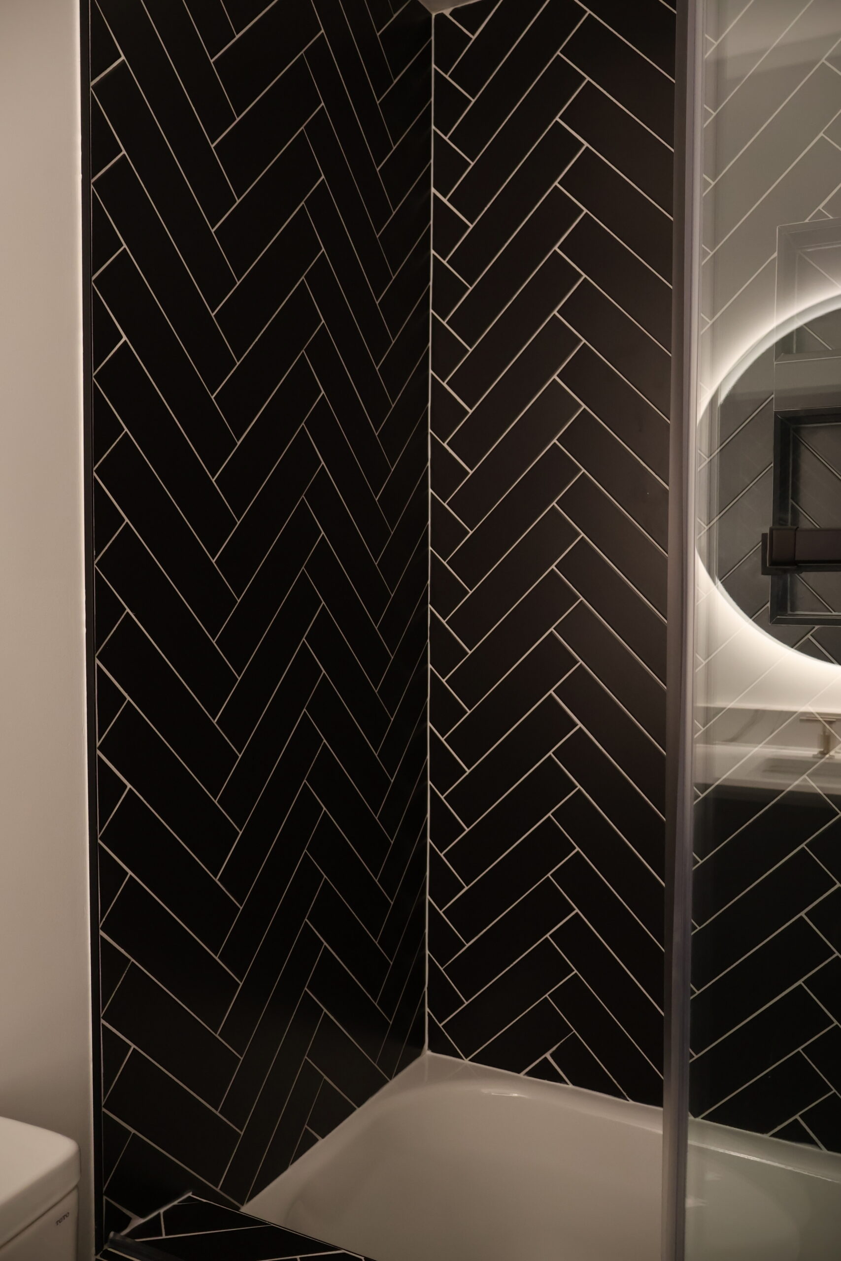 Detailed view of black porcelain tile hand laid in a herringbone pattern.