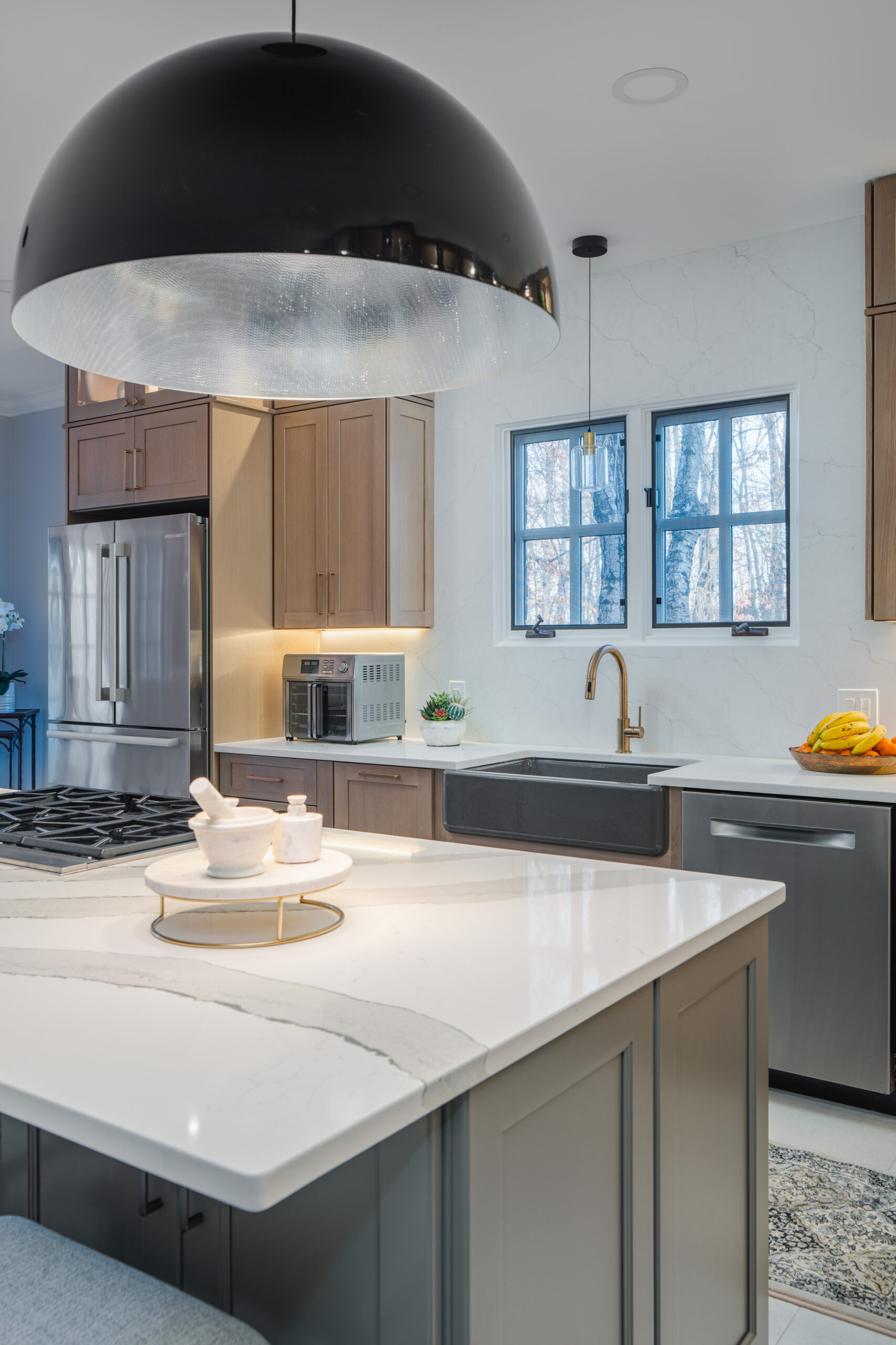 Detailed view of a waterfall-edge quartz island with dramatic gray veining under industrial black pendant lights.