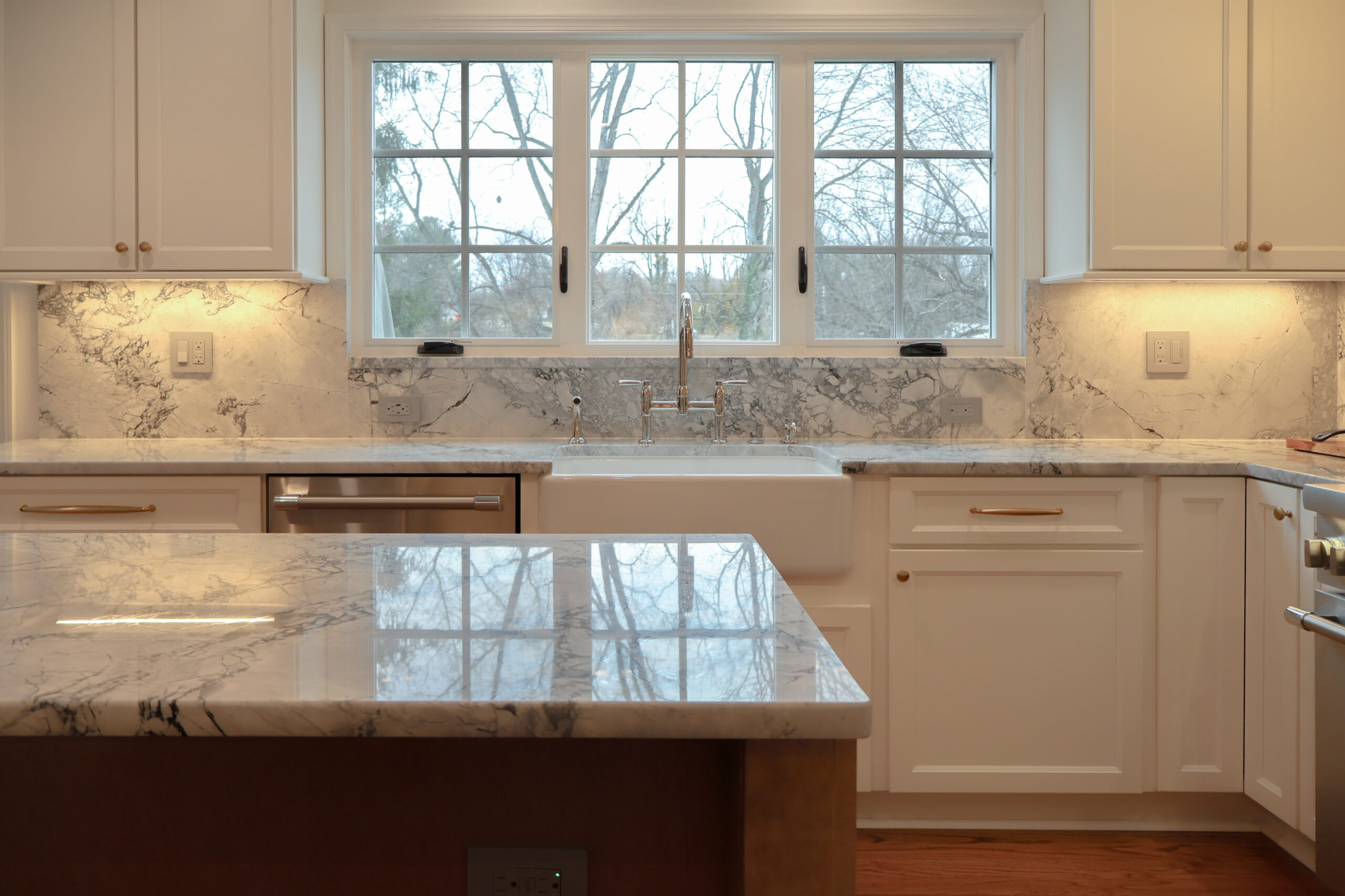 Historic Georgetown DC home featuring a white kitchen remodel with a large farmhouse sink, bridge faucet, and book-matched marble backsplash.