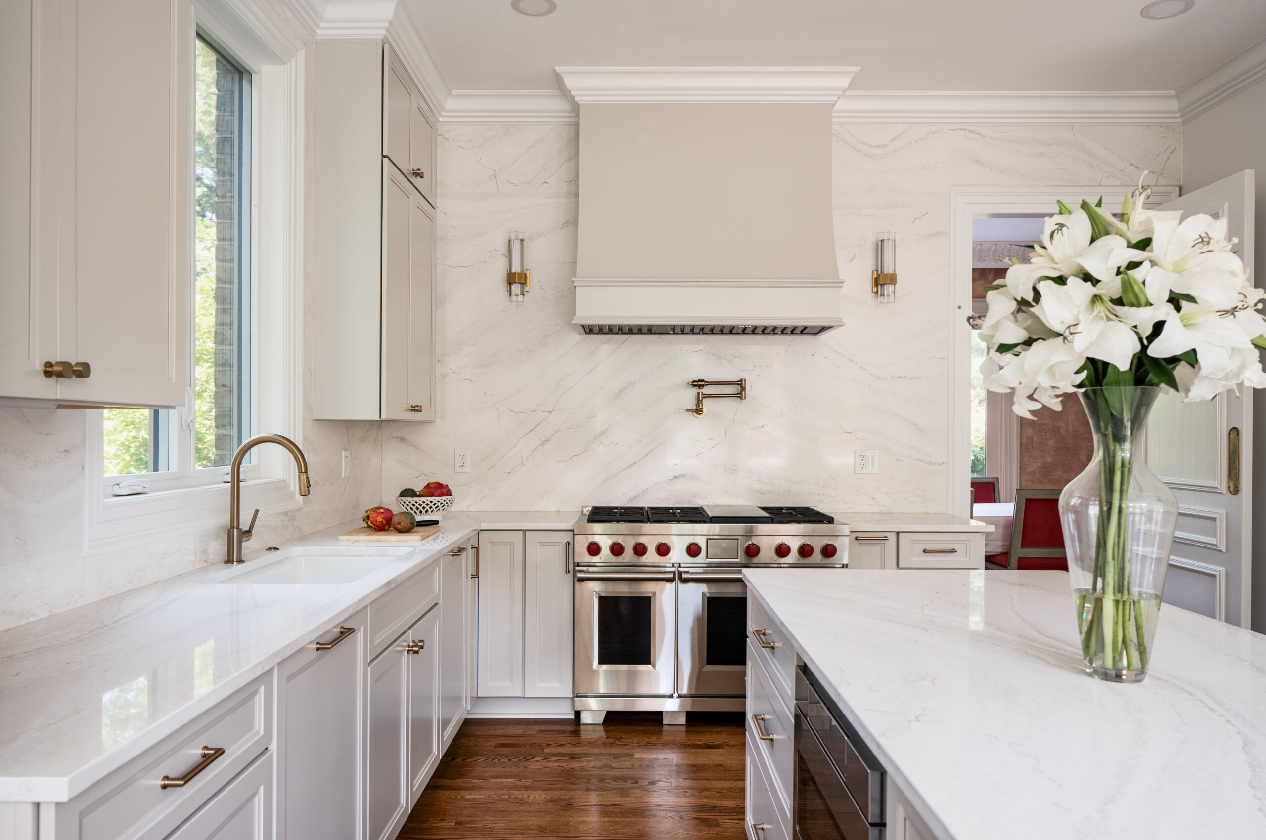 A high-end Wolf range stove positioned against a seamless white marble backsplash with modern gold sconces.