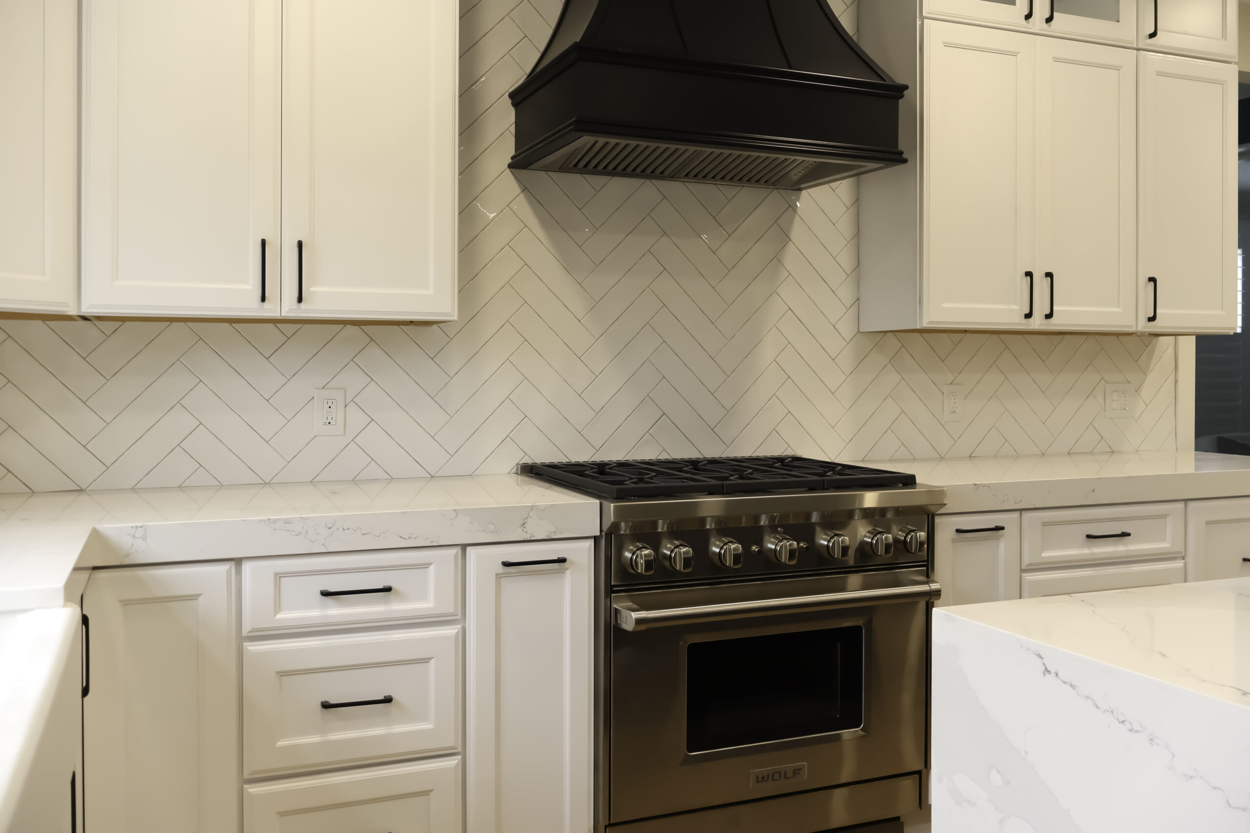 Close up of a Wolf 6 burner gas range surrounded by custom quartz countertops.