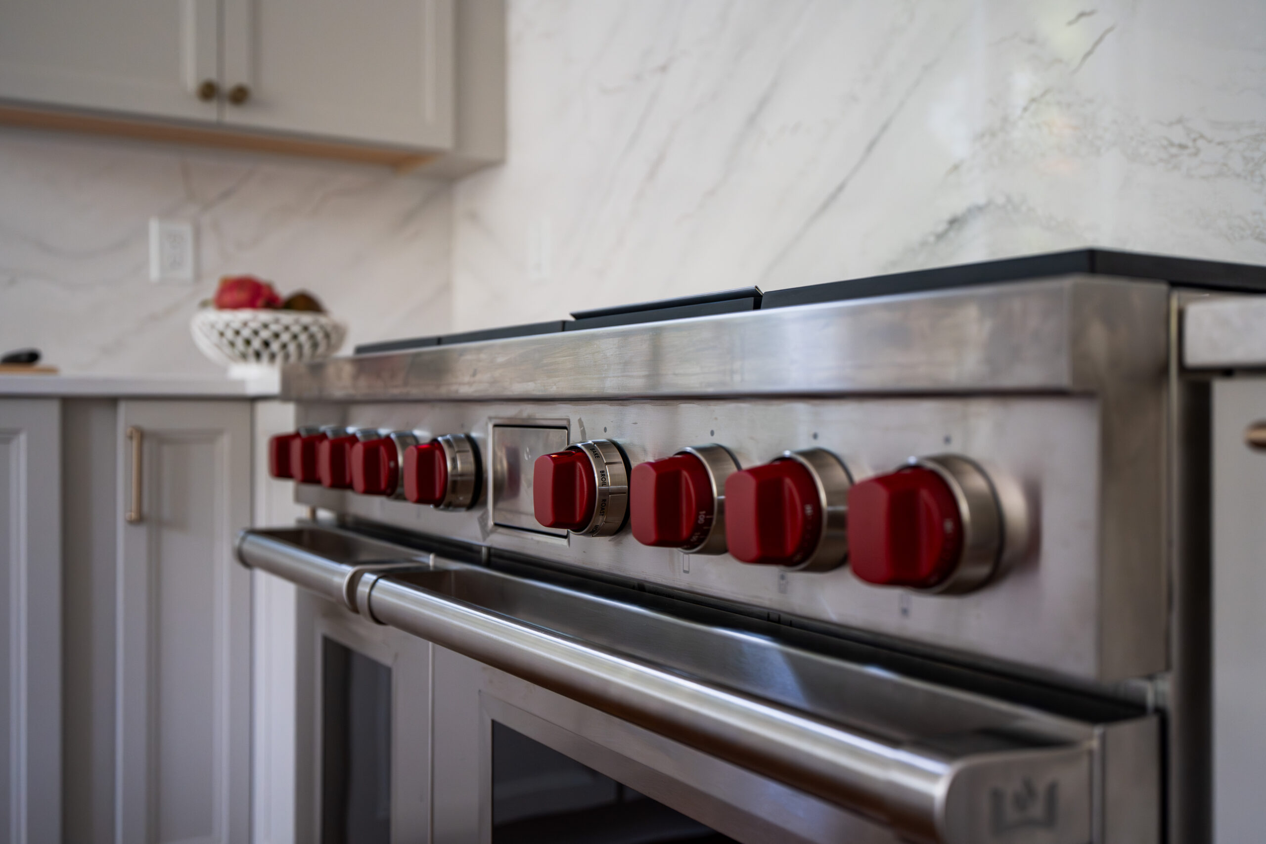 A close-up shot of the iconic red knobs on a professional stainless steel range.