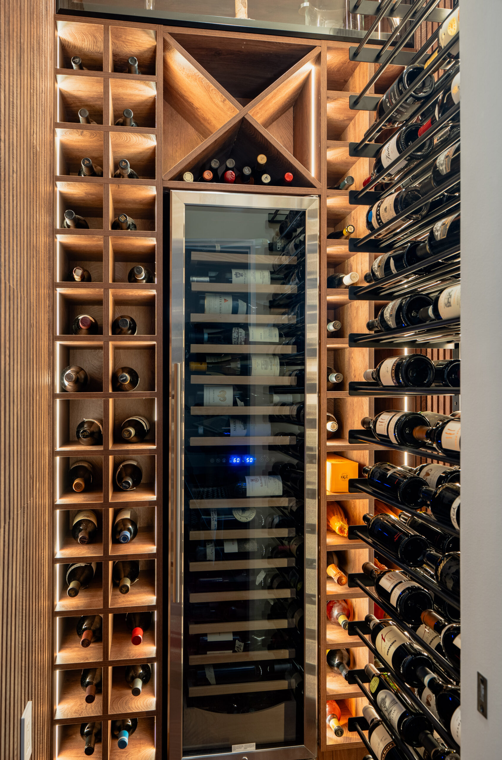 Custom built-in wine cellar with walnut grid storage racks, diamond bottle bins, dual-zone wine cooler set to 60 and 50 degrees, and warm accent lighting in Washington DC luxury home