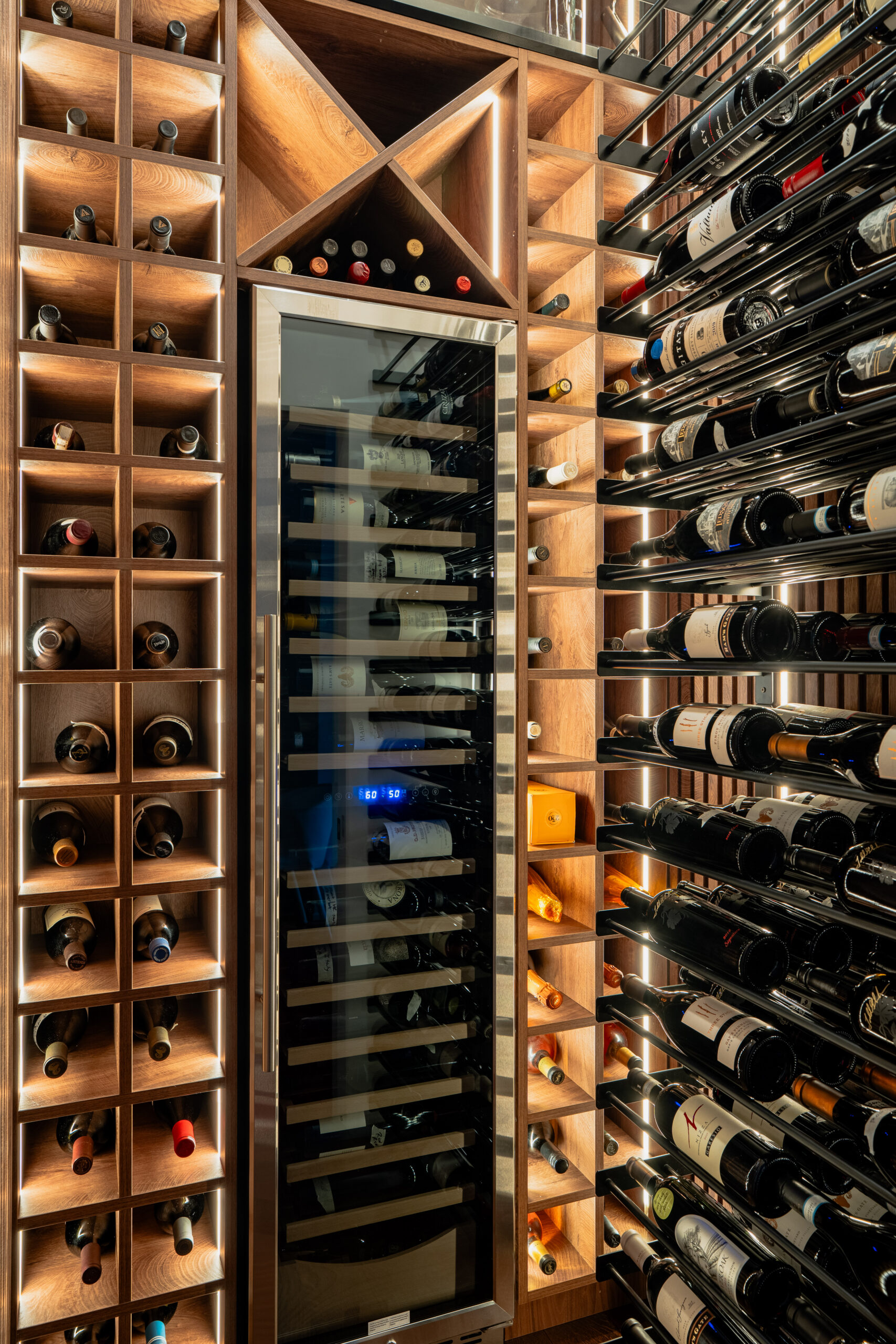 Luxury wine room featuring floor-to-ceiling walnut bottle racks, angled display shelving, diamond storage bins, and integrated dual-zone wine refrigerator in Washington DC interior design project