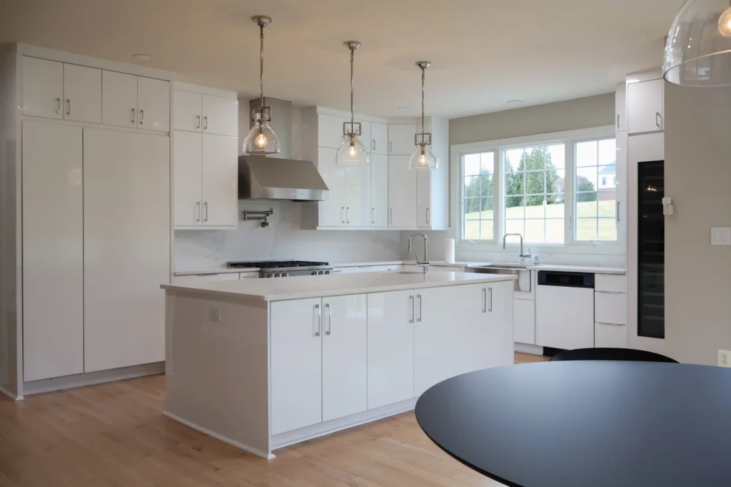 A stunning kitchen remodeling project in Leesburg, VA showcasing a massive marble-topped island with seating, elegant gold pendant lights, and floor-to-ceiling perimeter cabinetry integrated with professional-grade stainless steel appliances.