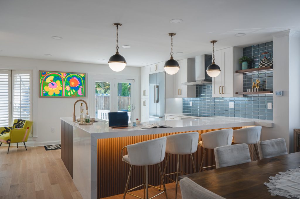 Condo kitchen remodeling in Washington DC featuring white shaker cabinets with brass hardware, teal blue stacked tile backsplash, large wood-panel island with quartz countertop, and black globe pendant lights